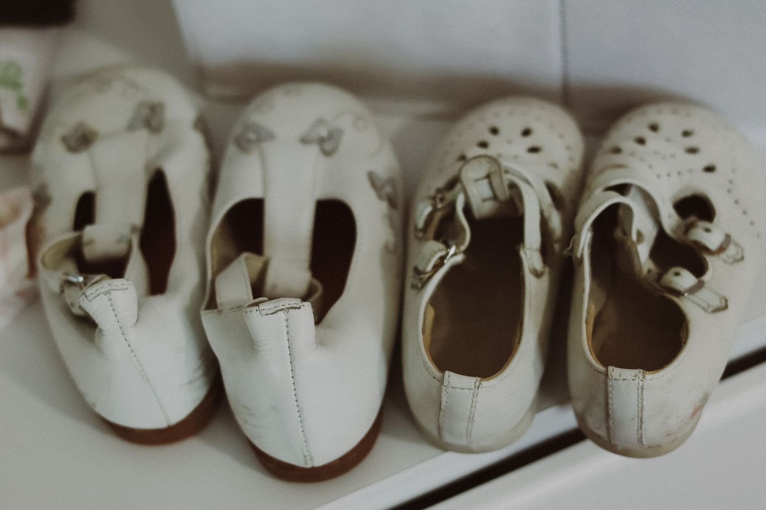 Row of tiny white baby shoes arranged in a line showing progression.