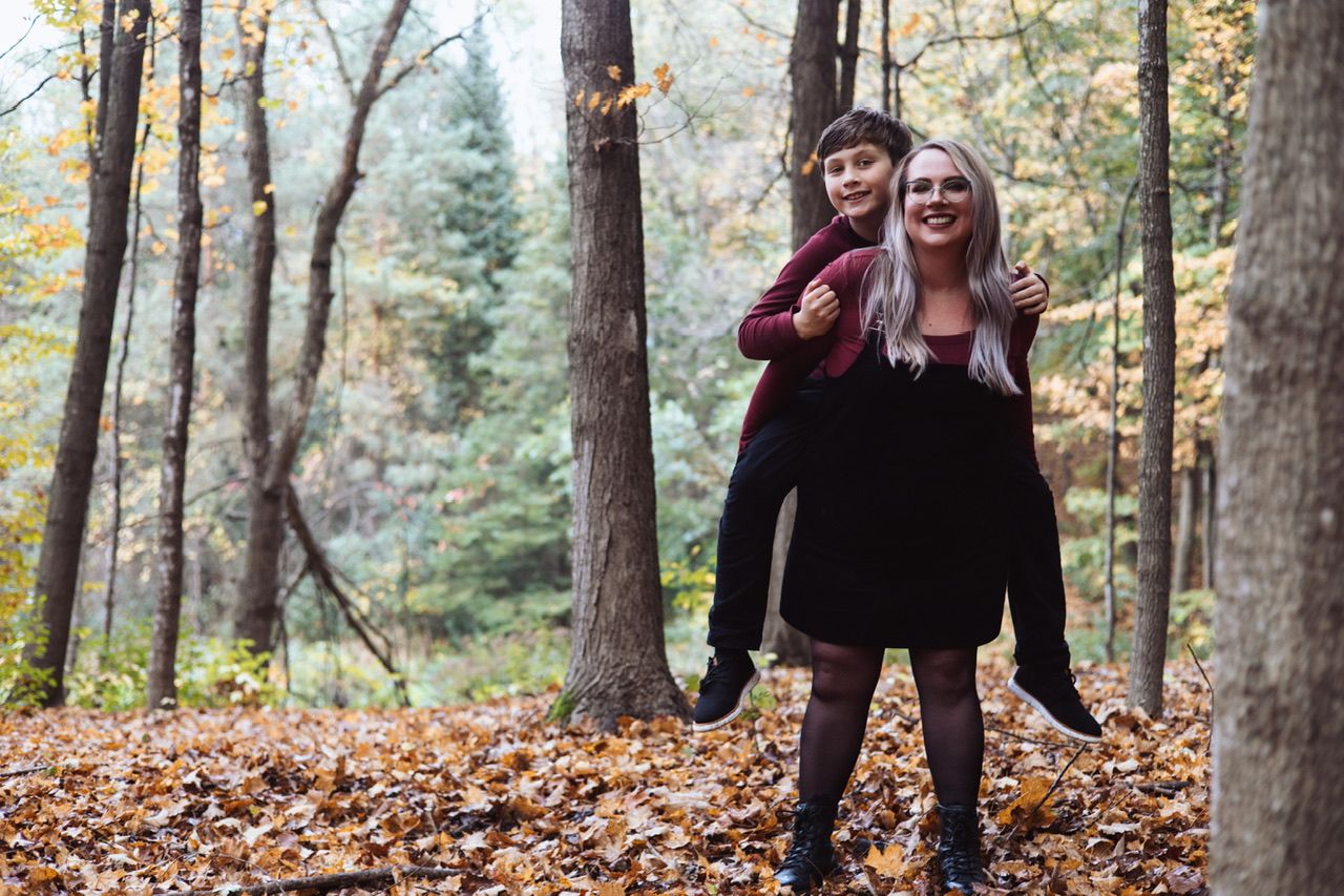 Autumn family photoshoot with people playing in fallen leaves.