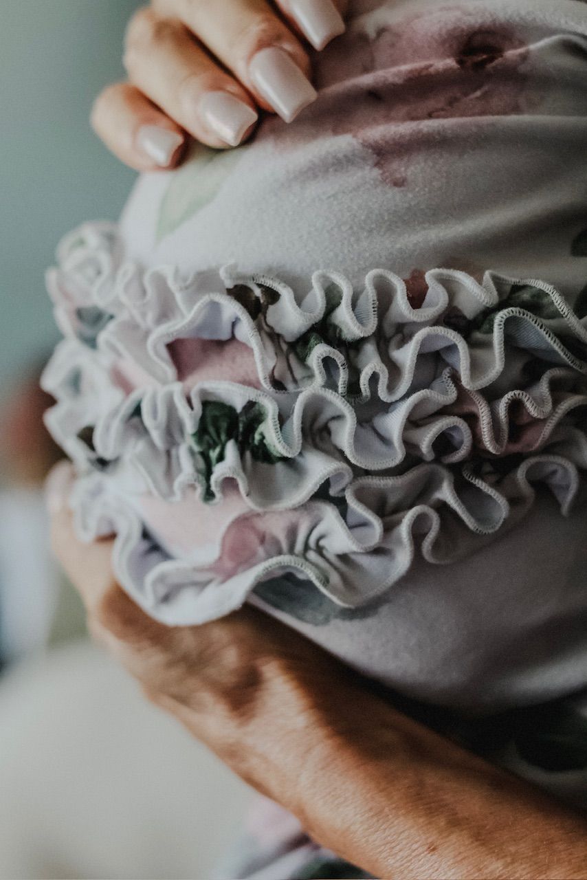 Close-up detail of hands holding ruffled fabric with delicate lace details.