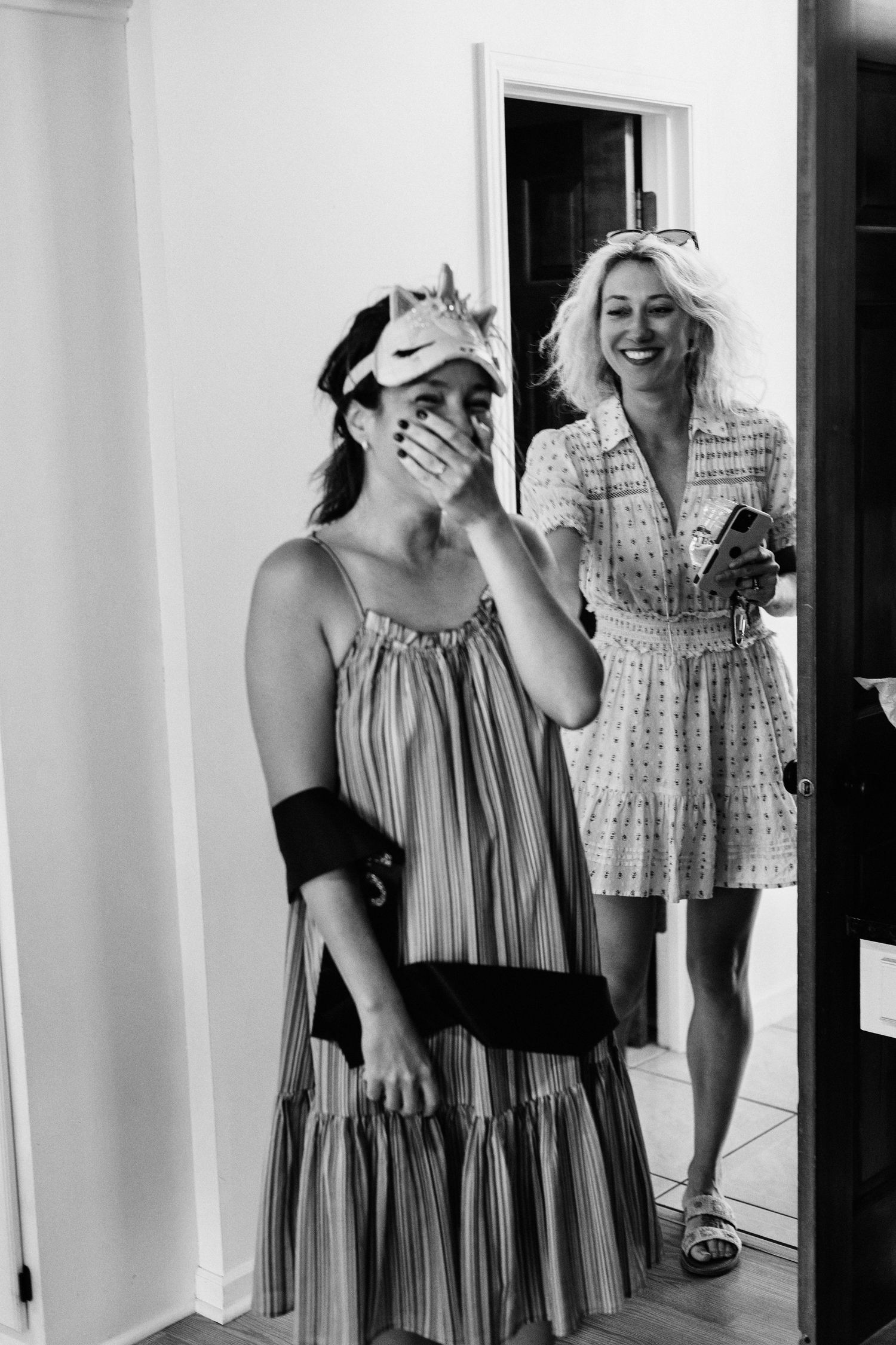 Black and white photo of friends laughing and celebrating together indoors.