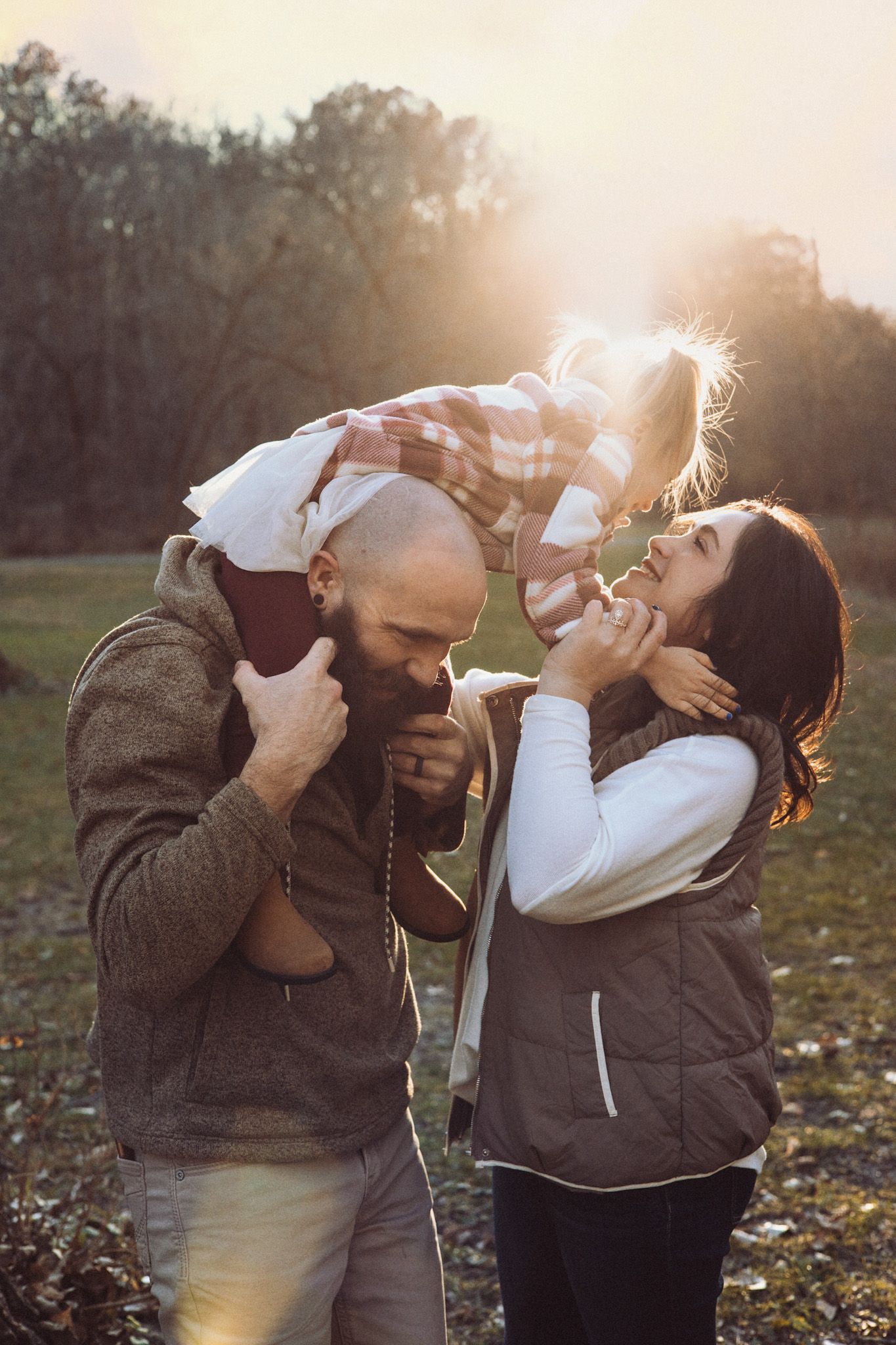Playful family moments captured at sunset in a fall field with golden light.