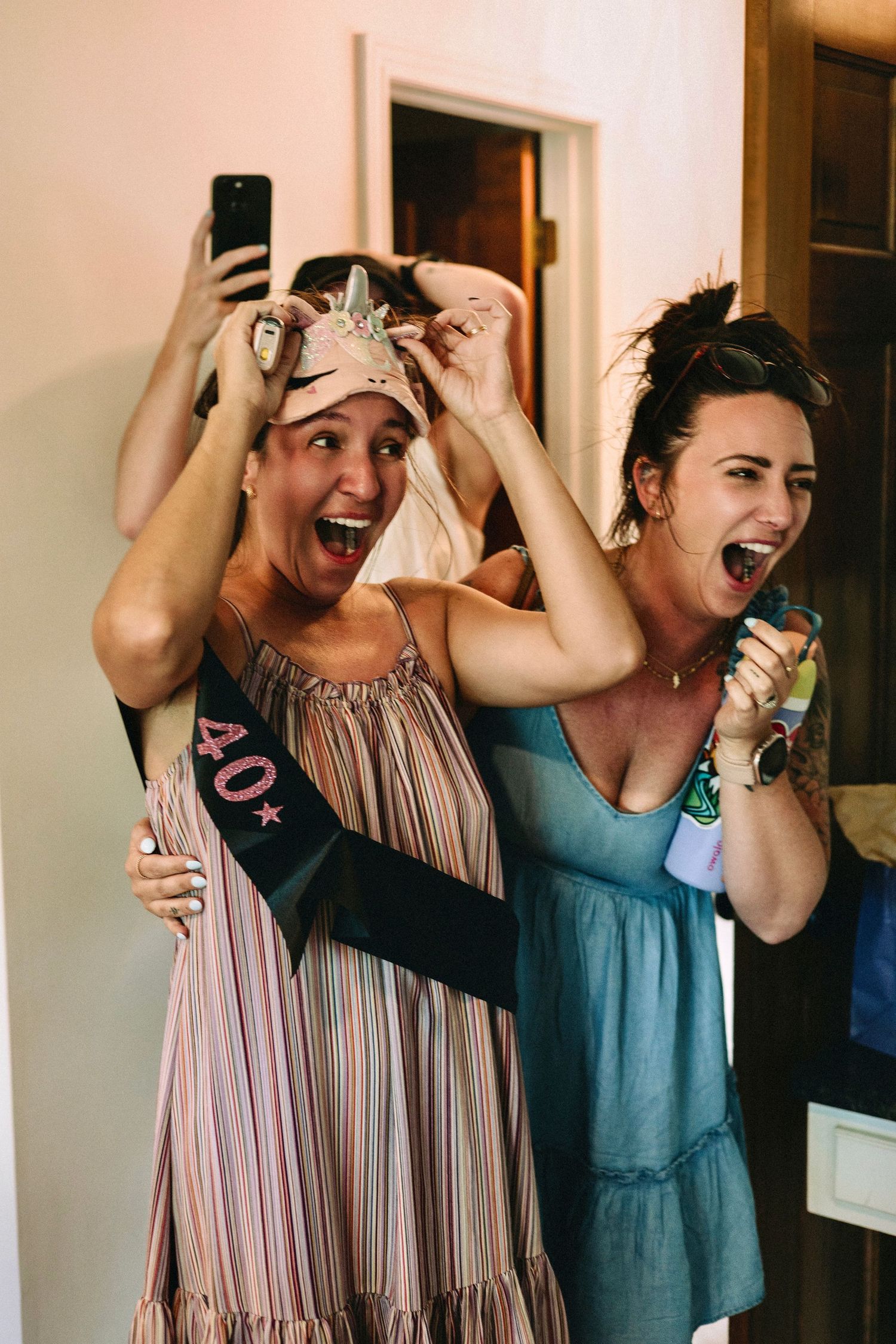 Two excited friends celebrating with tiaras and party accessories.