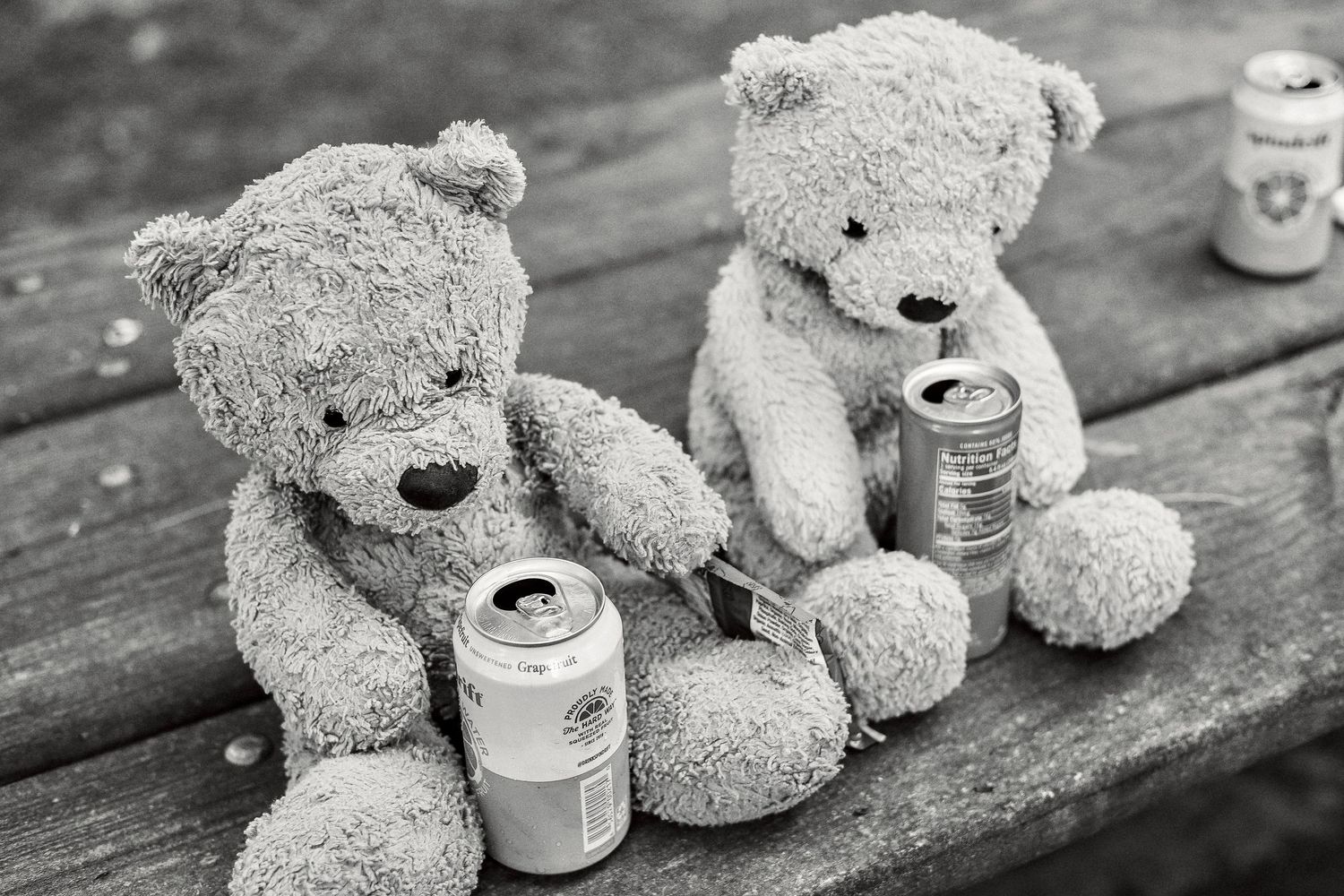 Plush teddy bears with paint supplies arranged on wooden surface.
