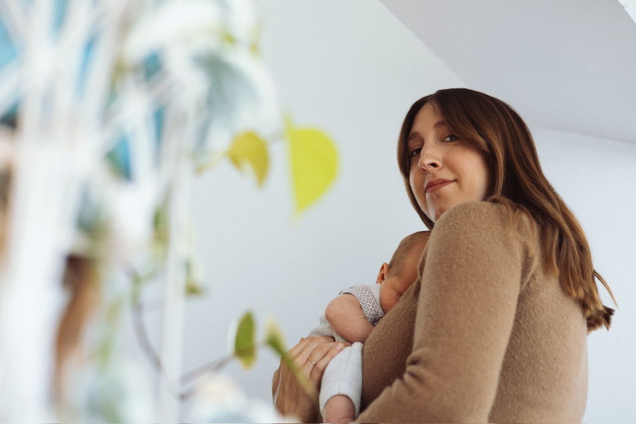 Person hugging a brown pillow in a bright room with decorative elements.