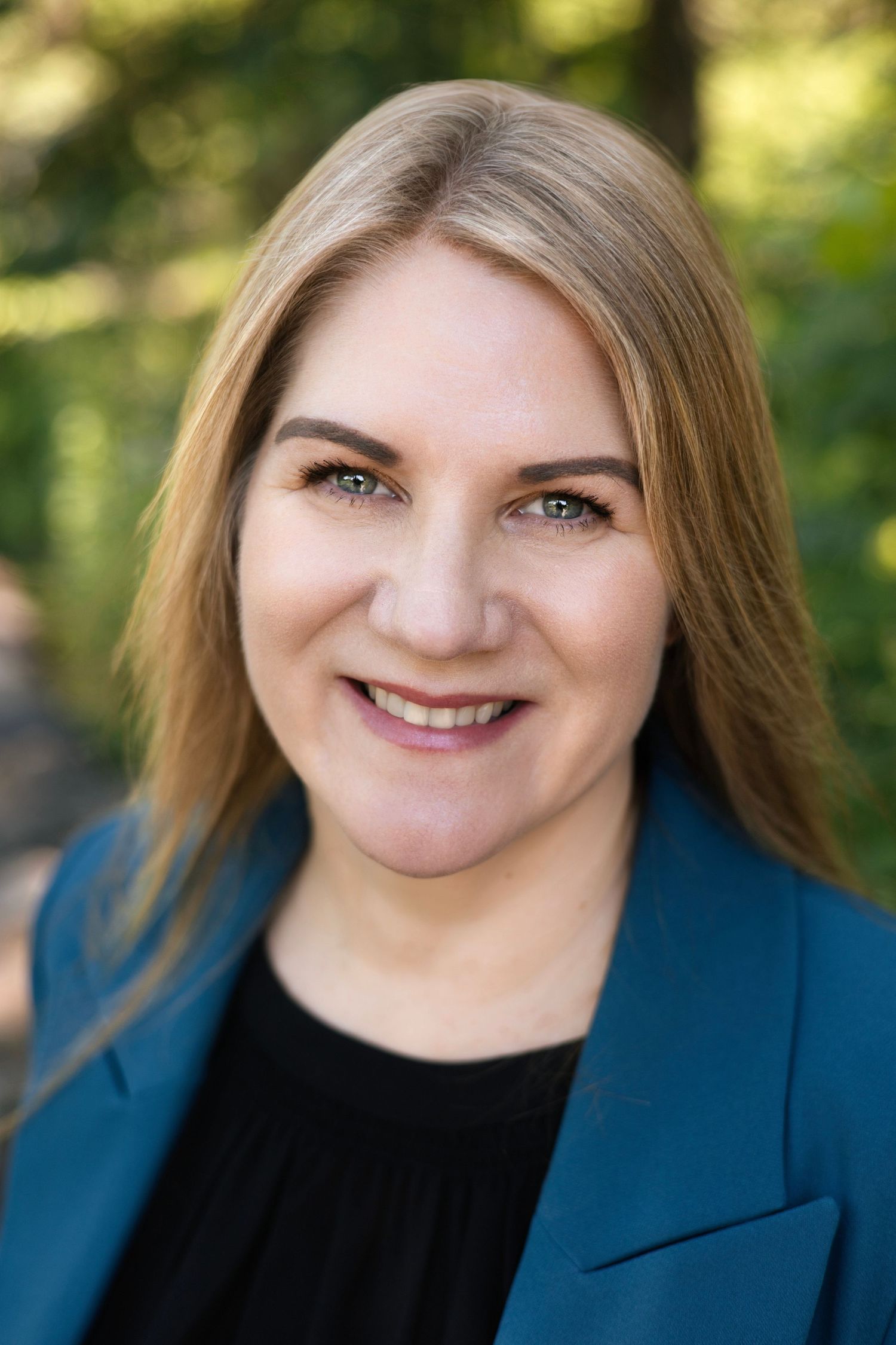 Professional headshot of a woman in a blue blazer smiling warmly at the camera.