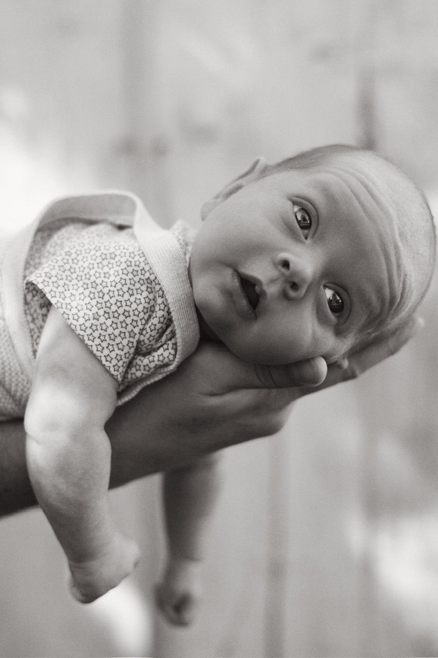 A baby in a polka dot outfit lies on their side in black and white.