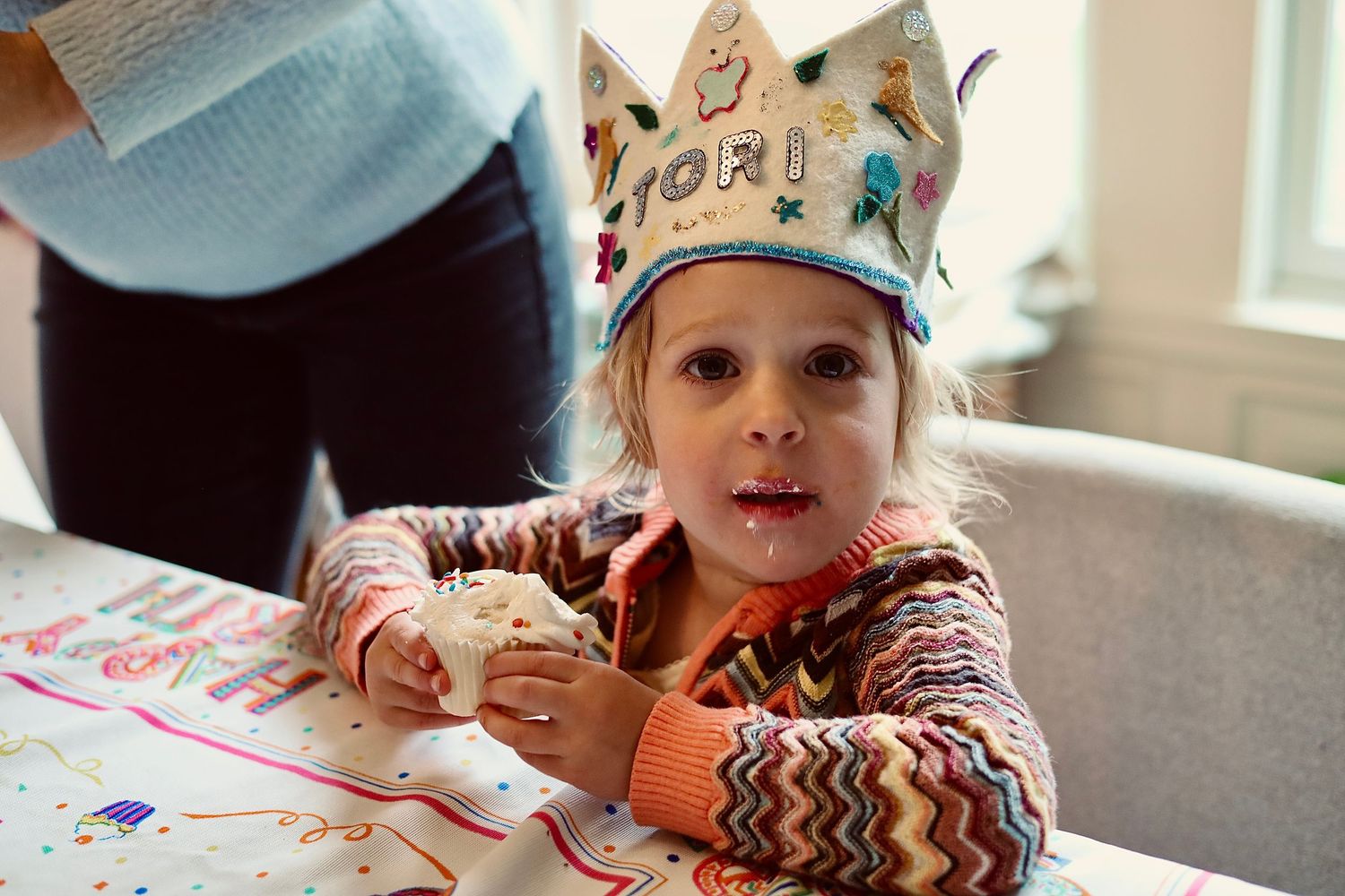 Child wearing a decorated paper crown while doing arts and crafts.