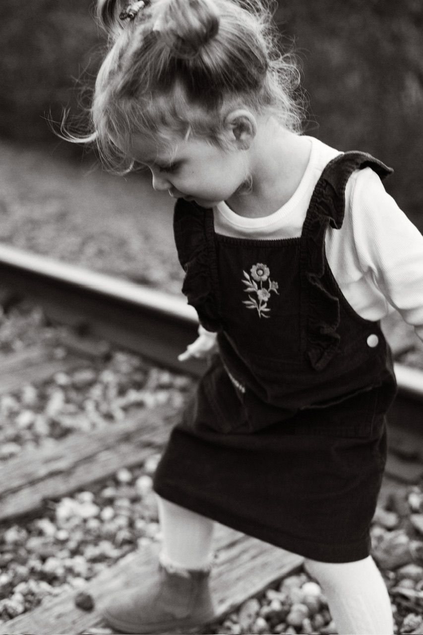 Black and white sequence of child exploring and walking along train tracks.