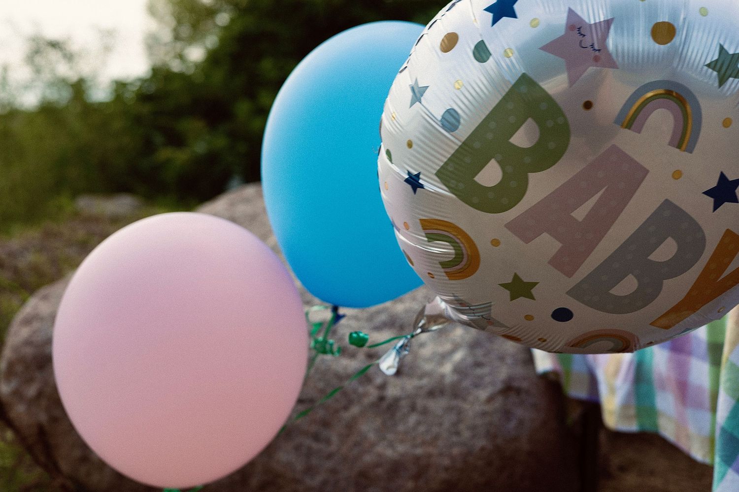 Pink and blue baby shower balloons arranged outdoors.