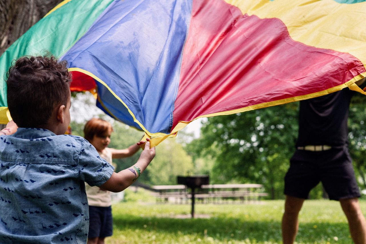 A rainbow parachute is stretched out during an outdoor activity.