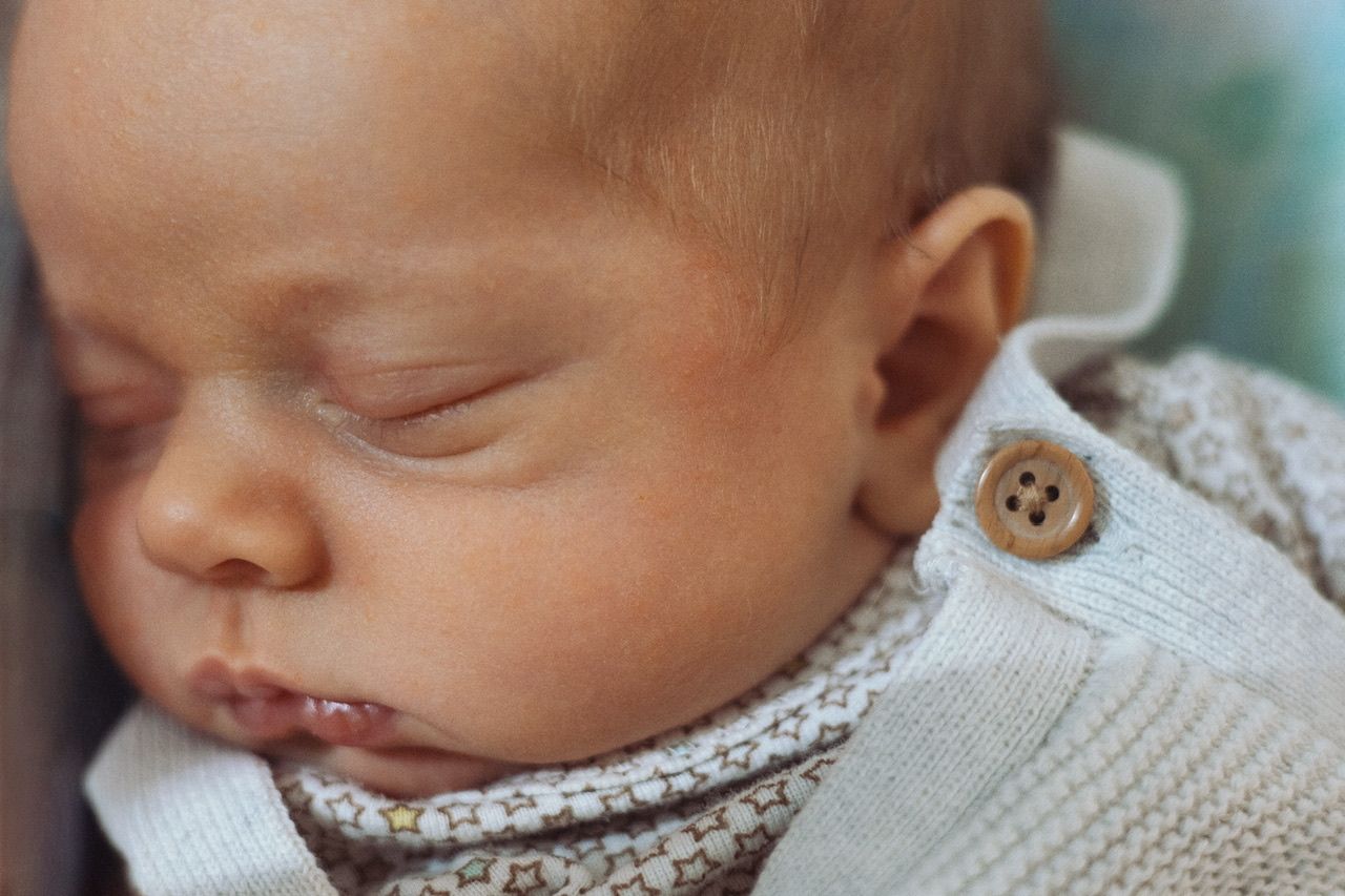 Close-up details of a sleeping newborn baby in soft lighting.