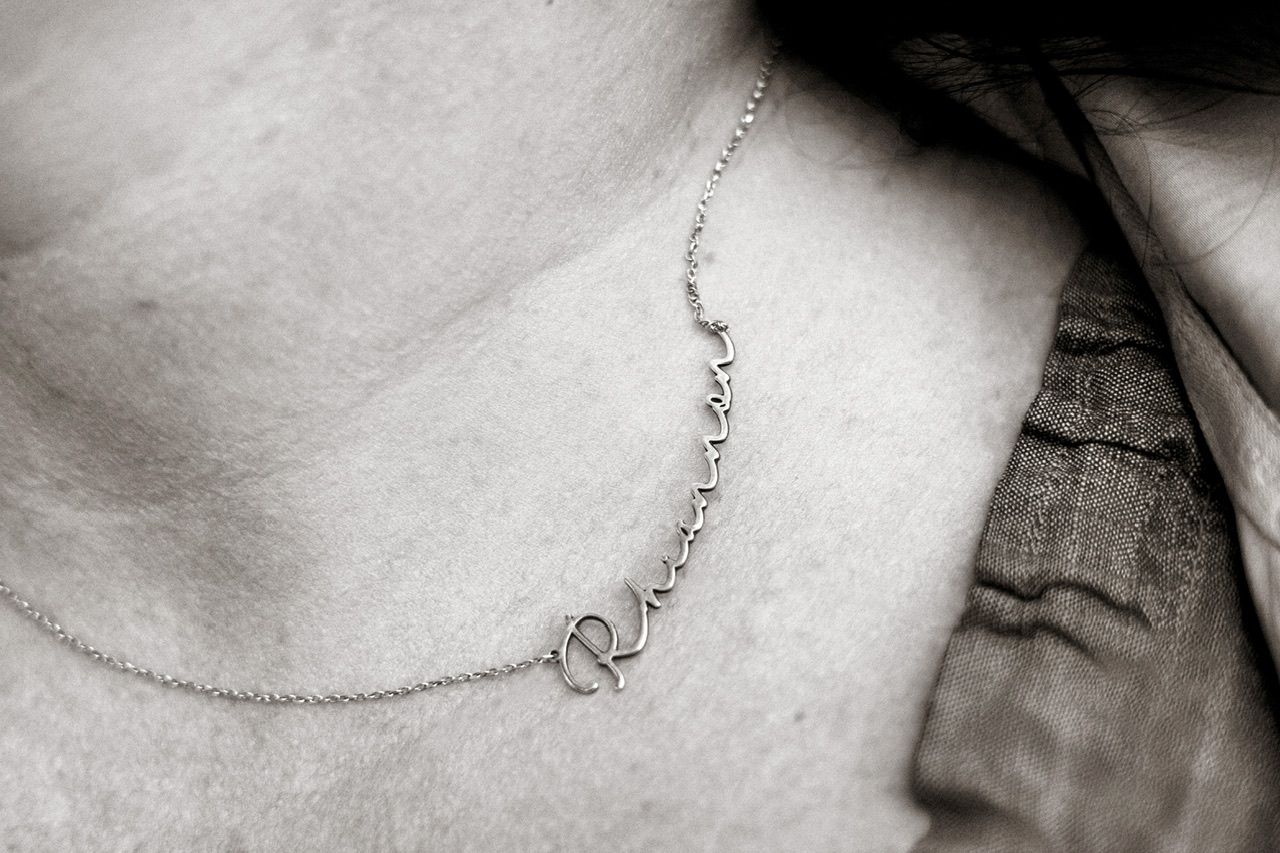 Close-up detail of a delicate silver necklace chain against a light background.