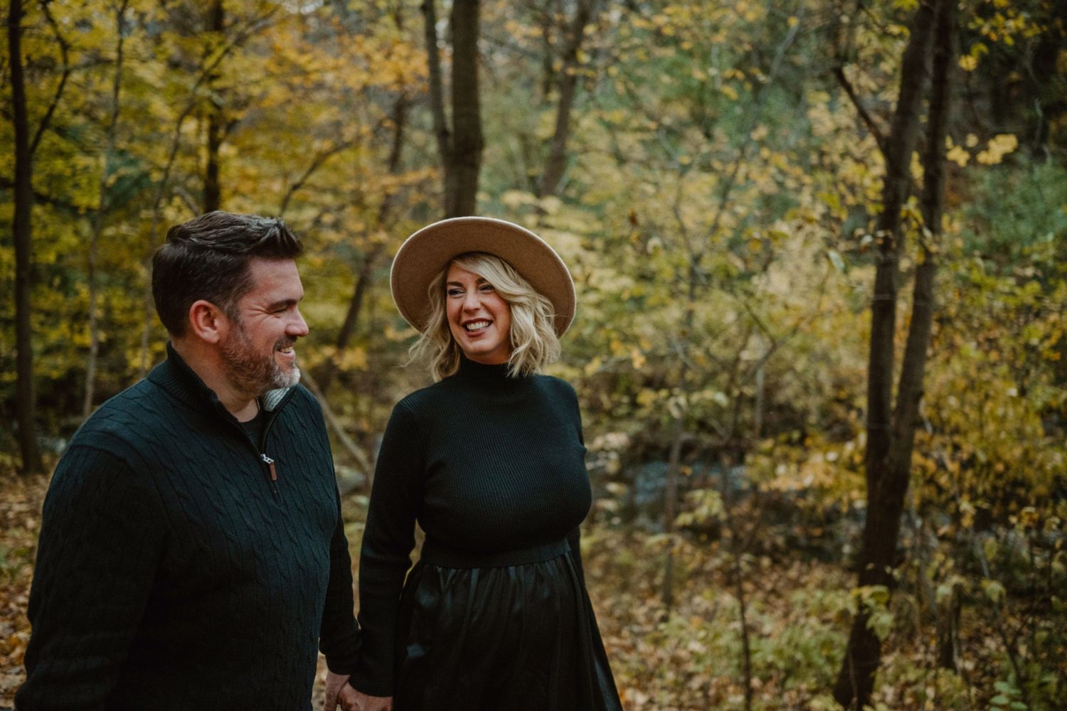 Candid autumn forest scene with people enjoying a moment among fall foliage.