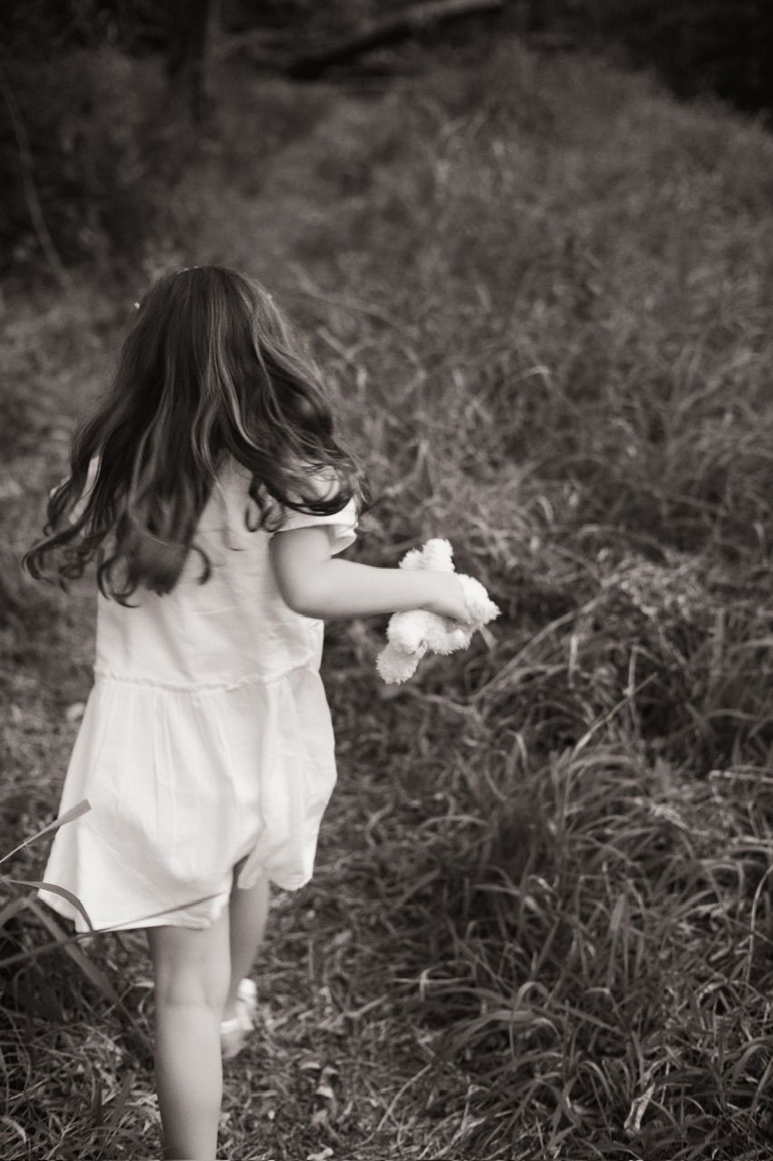 Black and white image of someone running through tall grass in a white summer dress.