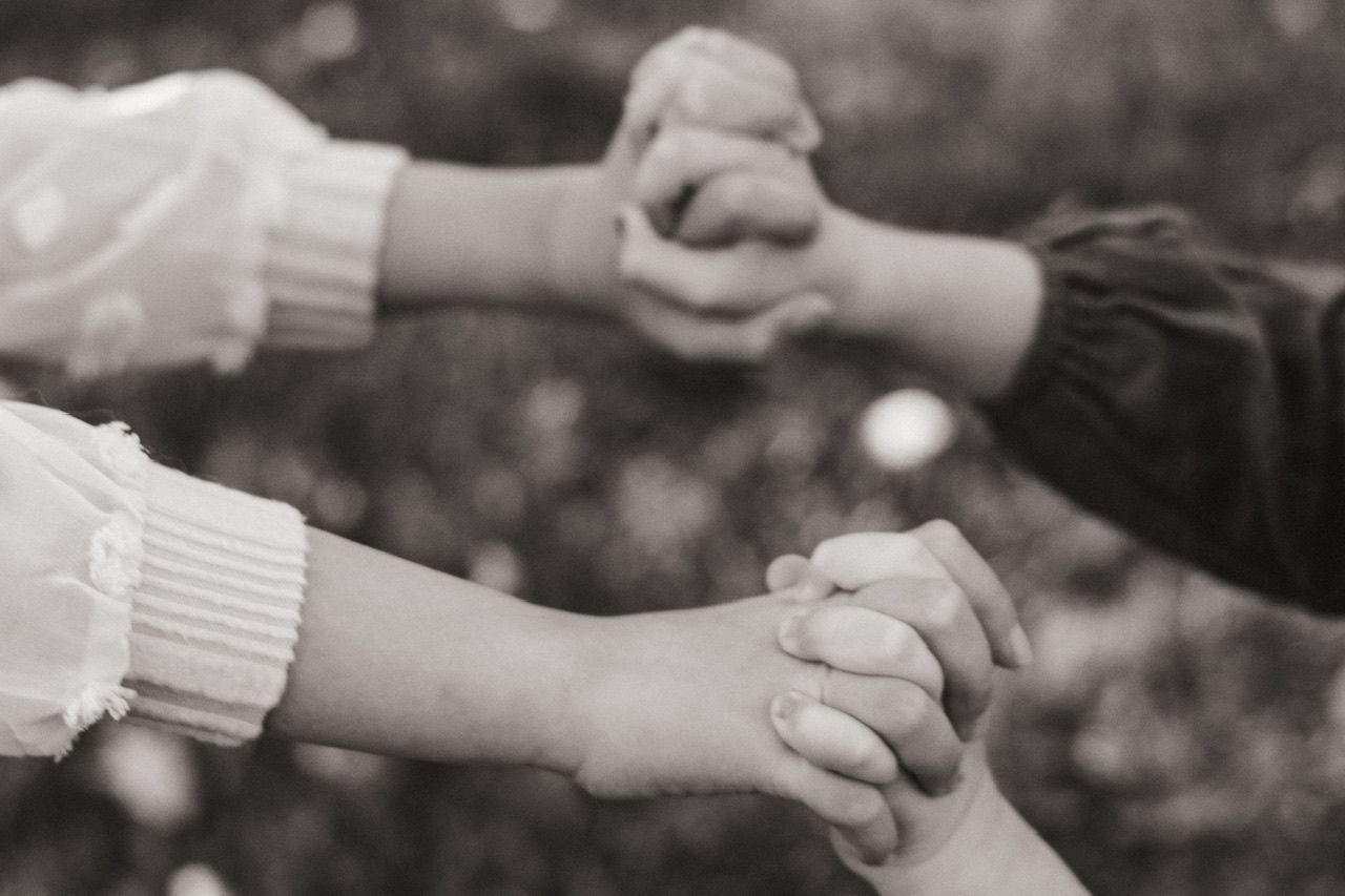 Close-up of hands reaching and connecting in black and white photography.