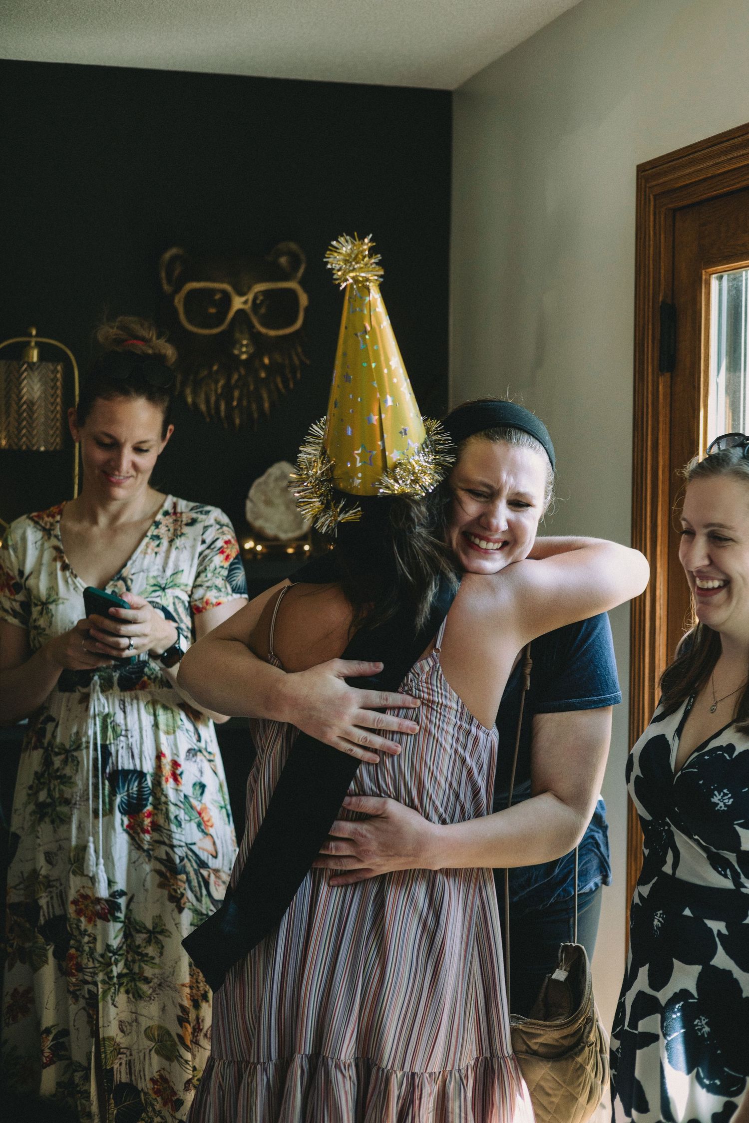 Friends sharing laughter and hugs during an indoor celebration.