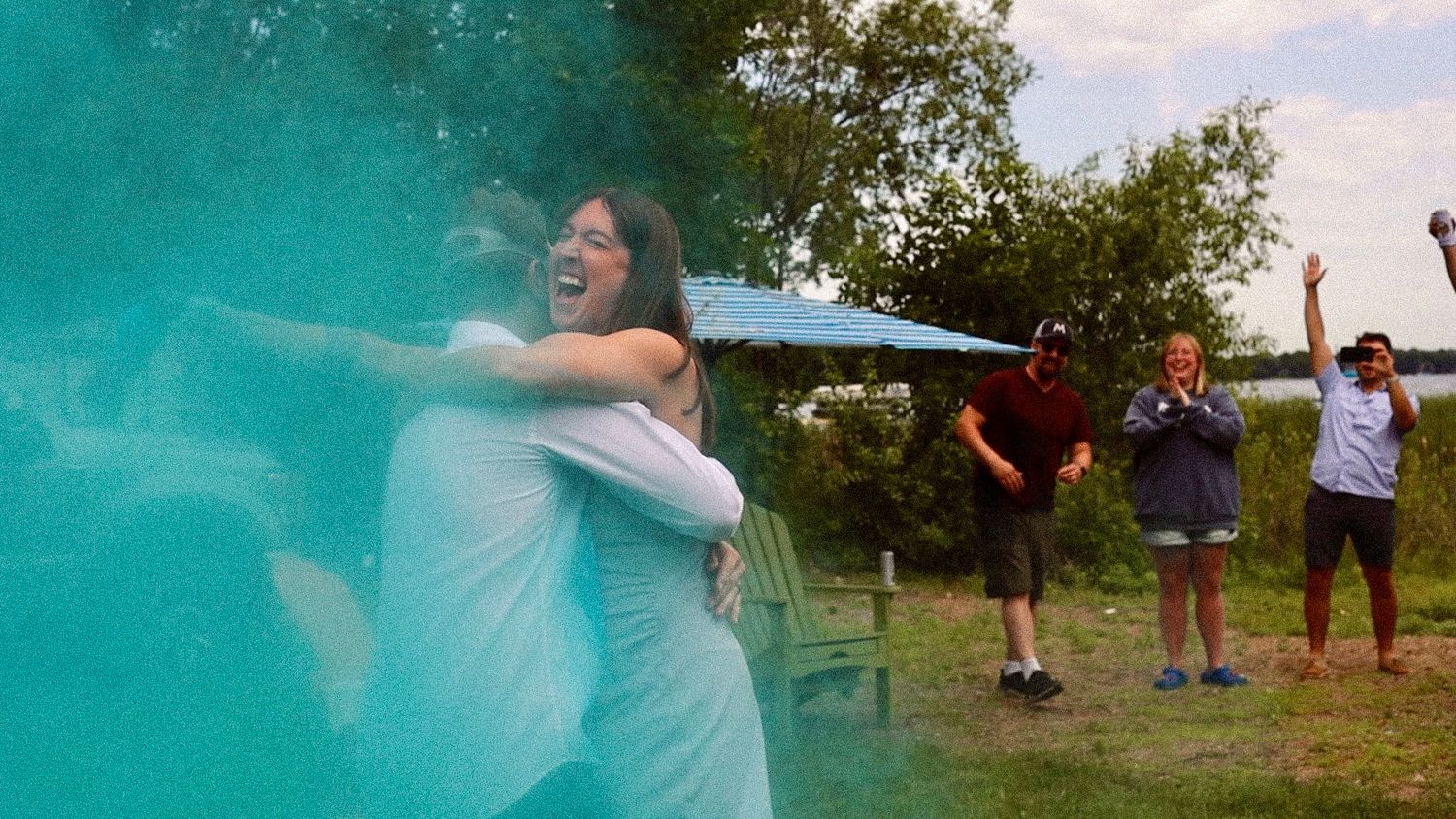 A gender reveal celebration with blue powder exploding outdoors.