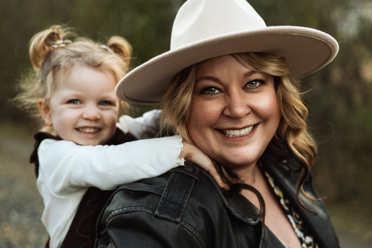 A joyful outdoor portrait showing a close bonding moment between parent and child wearing casual attire.