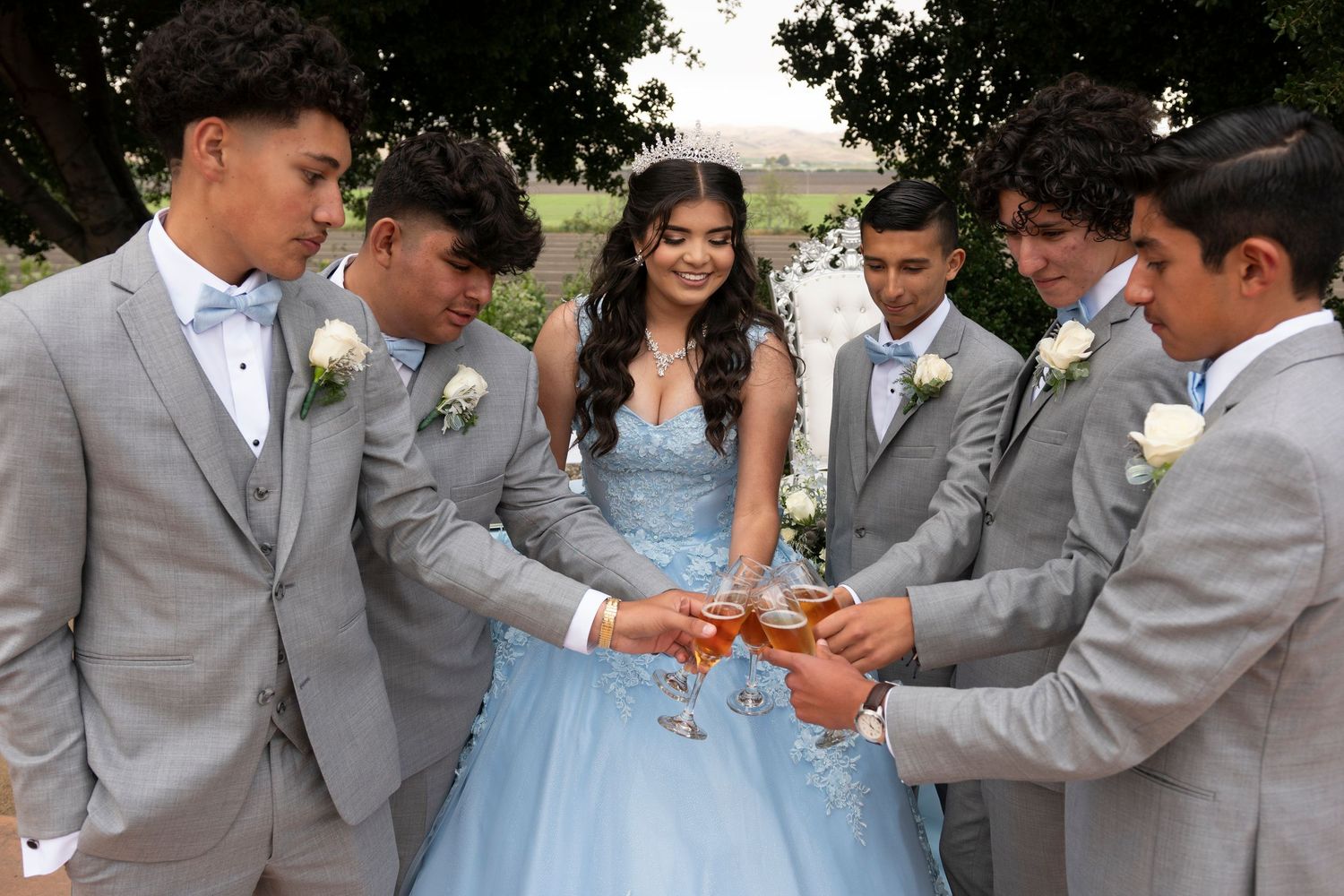 Wedding party in gray suits and light blue dress pose together outdoors.