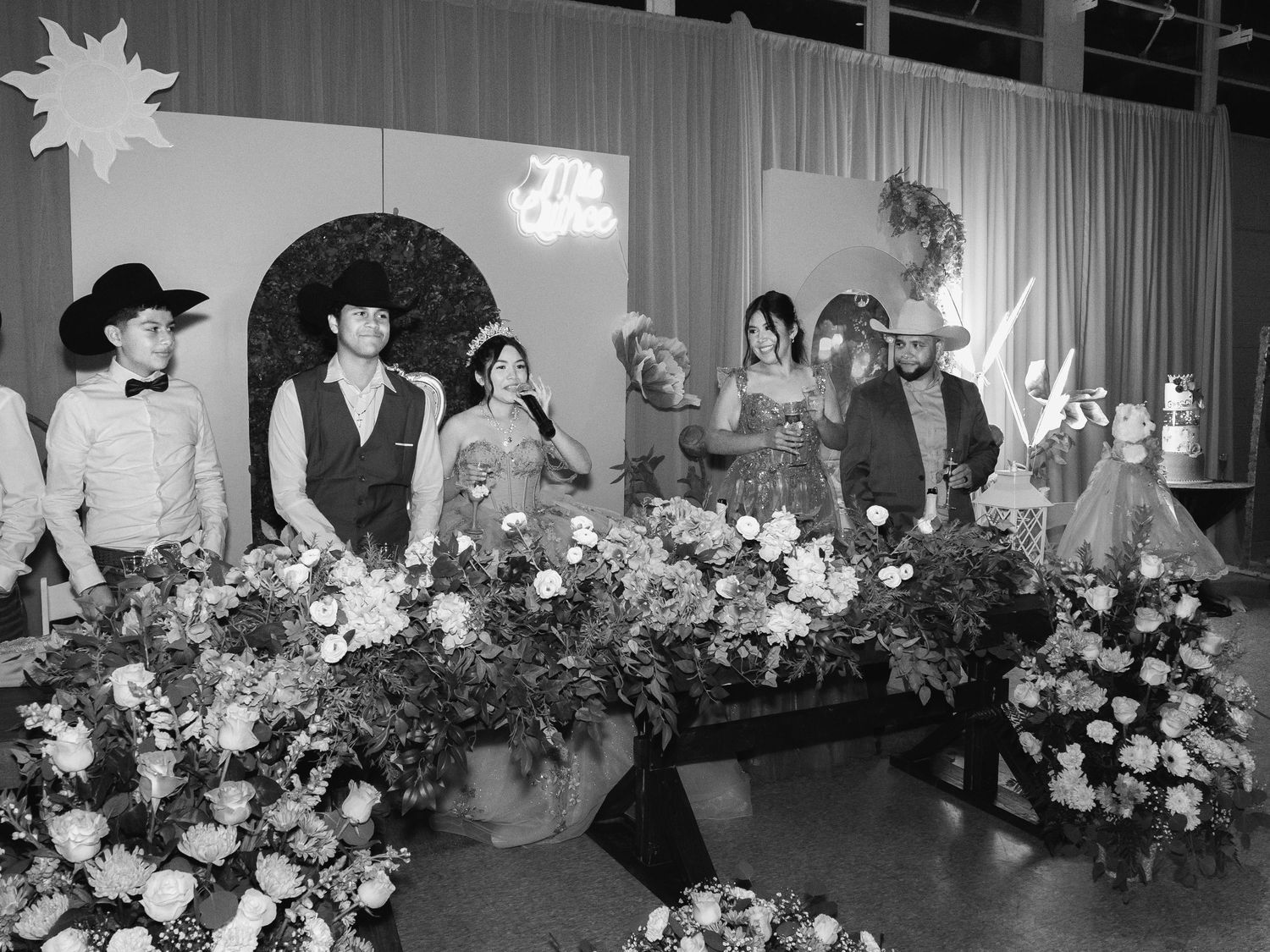 A black and white panoramic view of a wedding reception with floral arrangements decorating the tables.