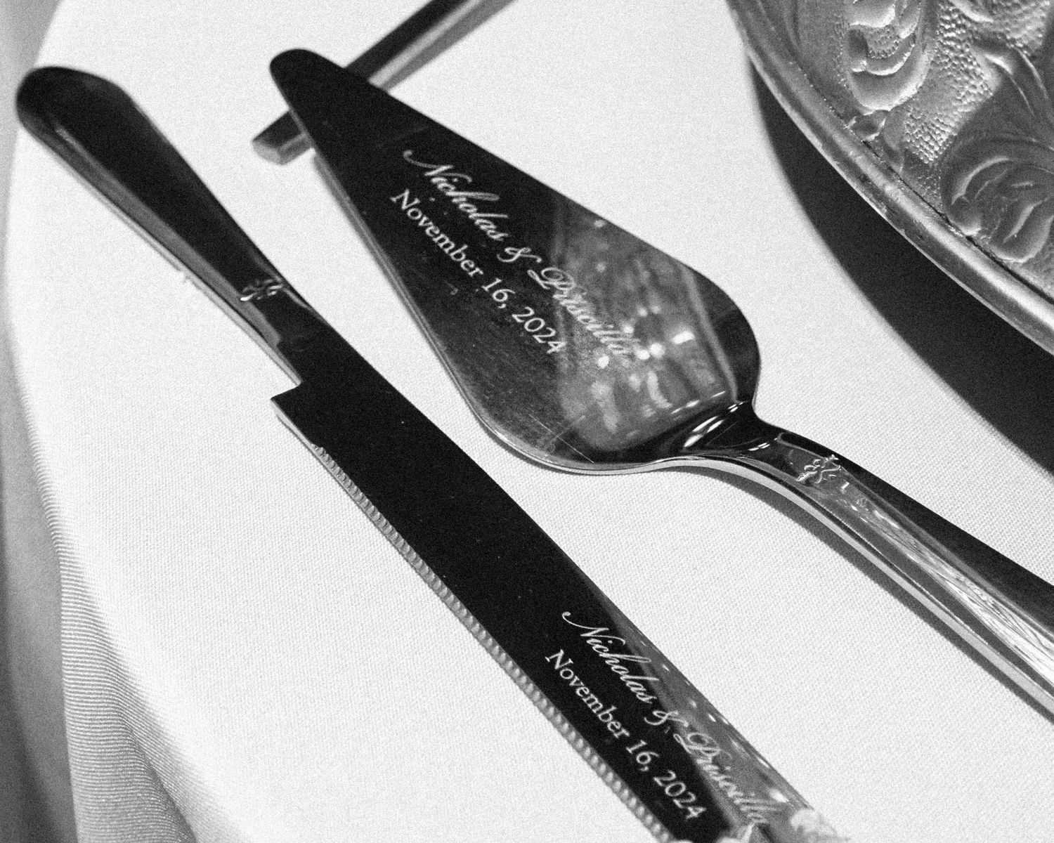 A collection of black and white knives arranged in a diagonal pattern showing their sleek metallic blades.