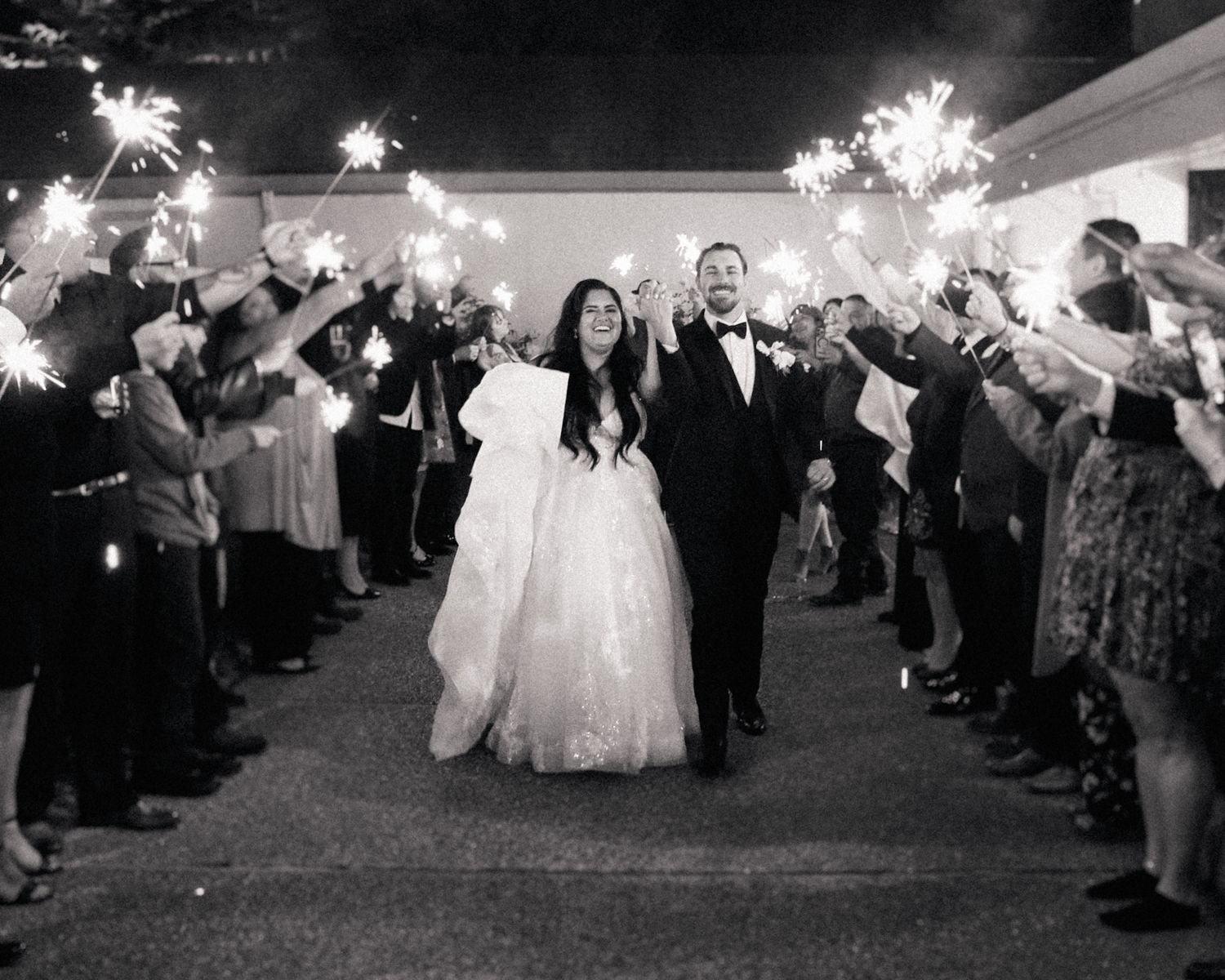 Wedding guests hold sparklers in the dark to create a magical sendoff tunnel for the newlyweds.