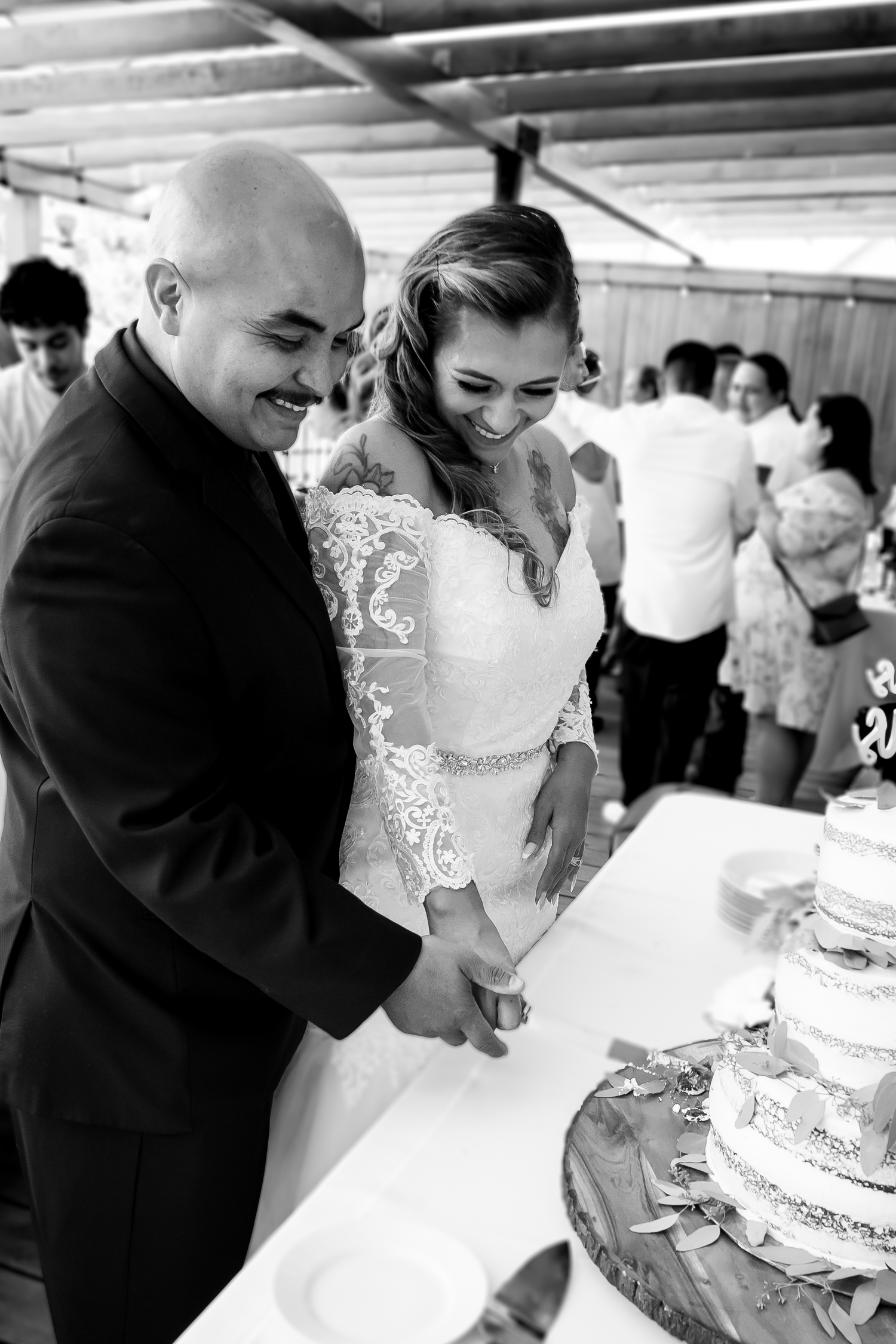 Wedding cake cutting moment captured in black and white photography.