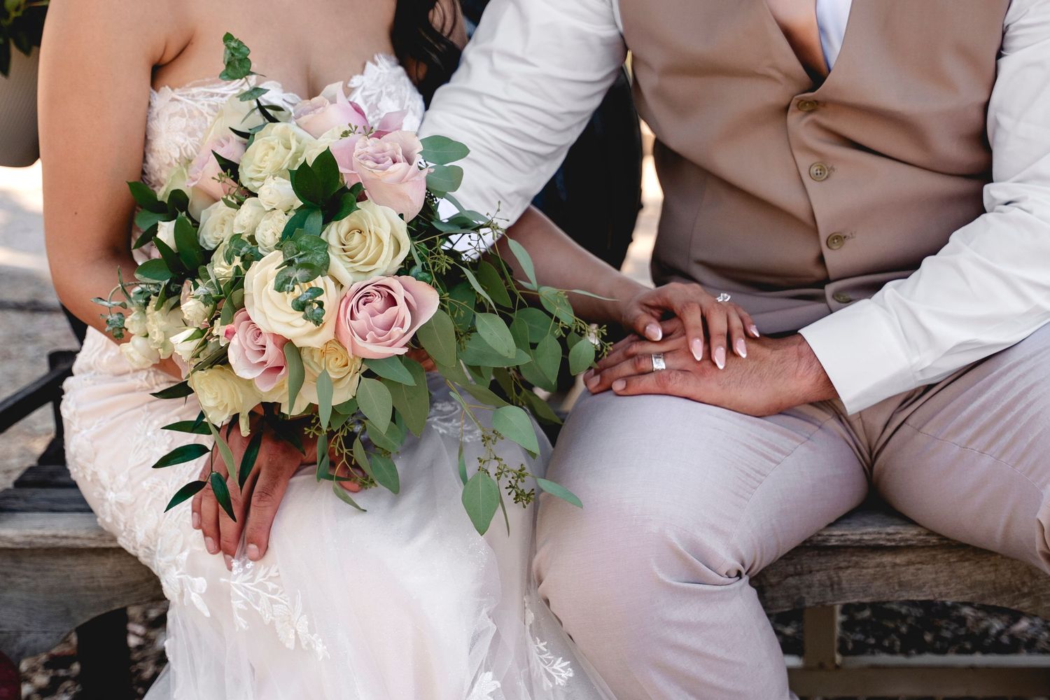 Elegant wedding bouquet with pink roses and greenery rests on white fabric.