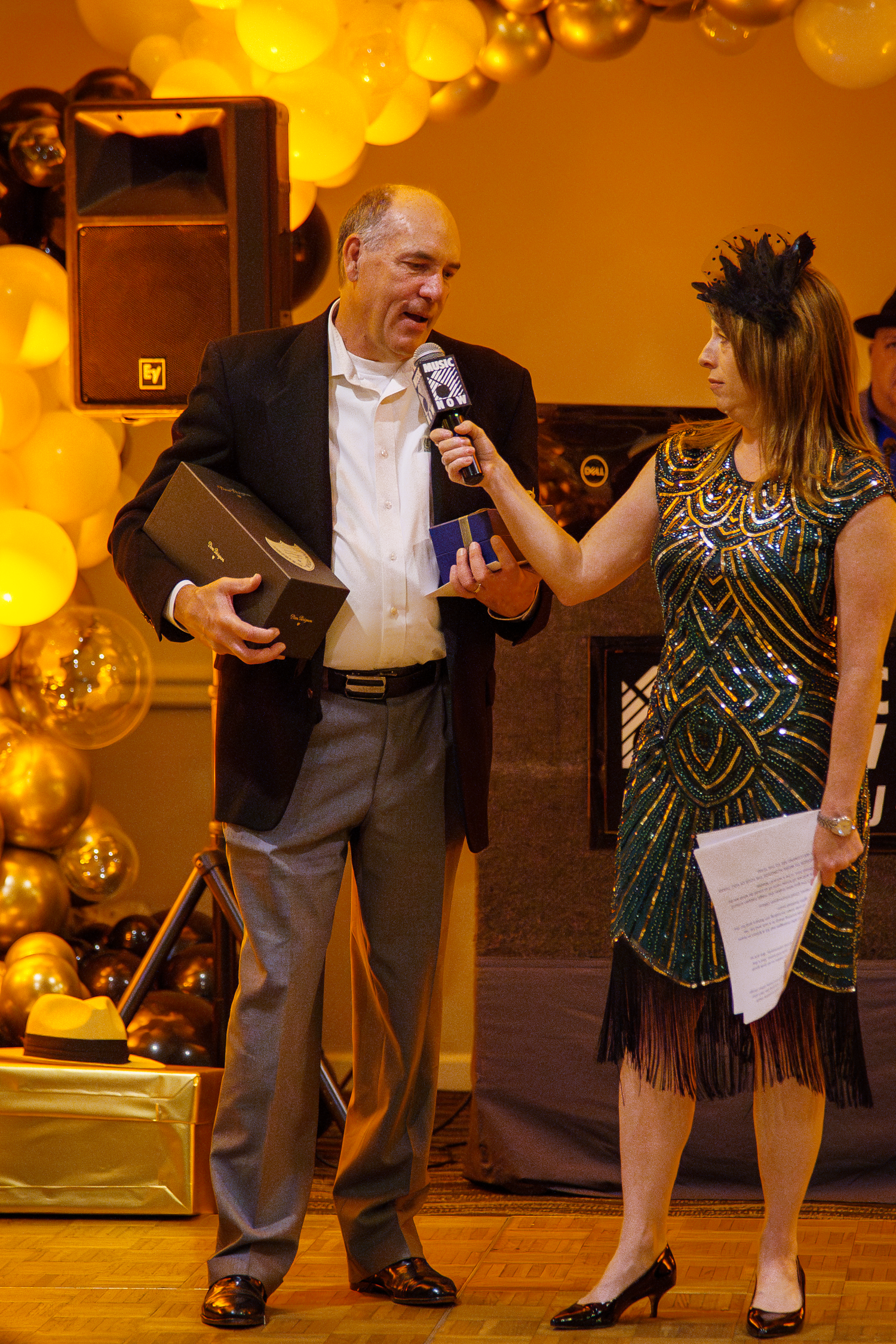Man receiving award at a glamorous Great Gatsby themed gala event with gold balloons and decorations.