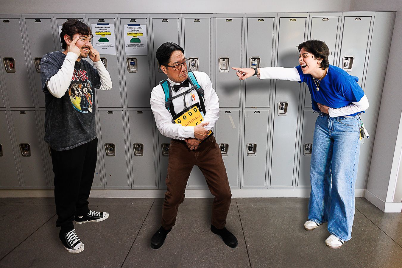 Three people posing dramatically by school lockers, one pointing, one ducking, one covering ears.
