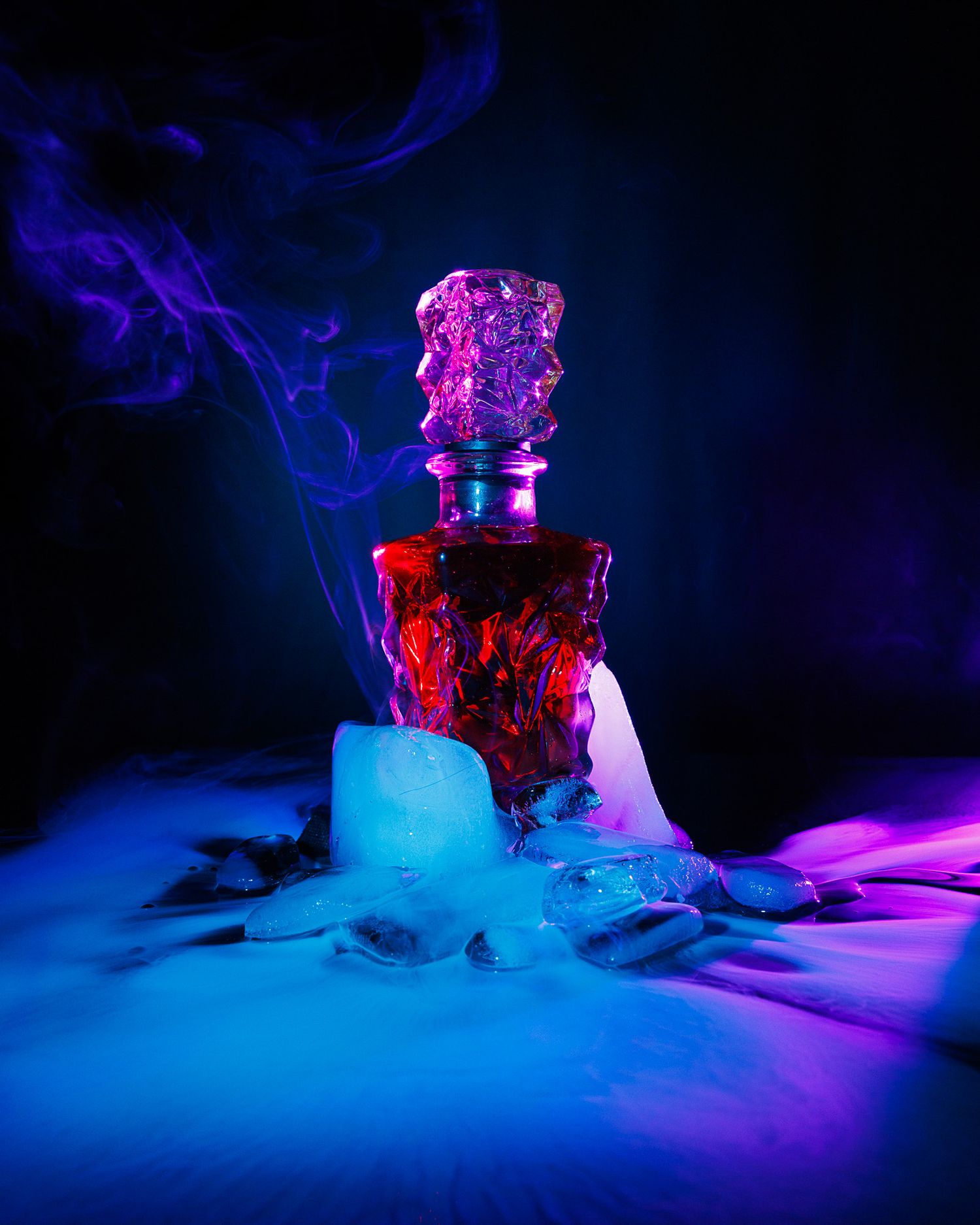 A dramatic red decorative bottle surrounded by dry ice fog and purple smoke in dark moody lighting.