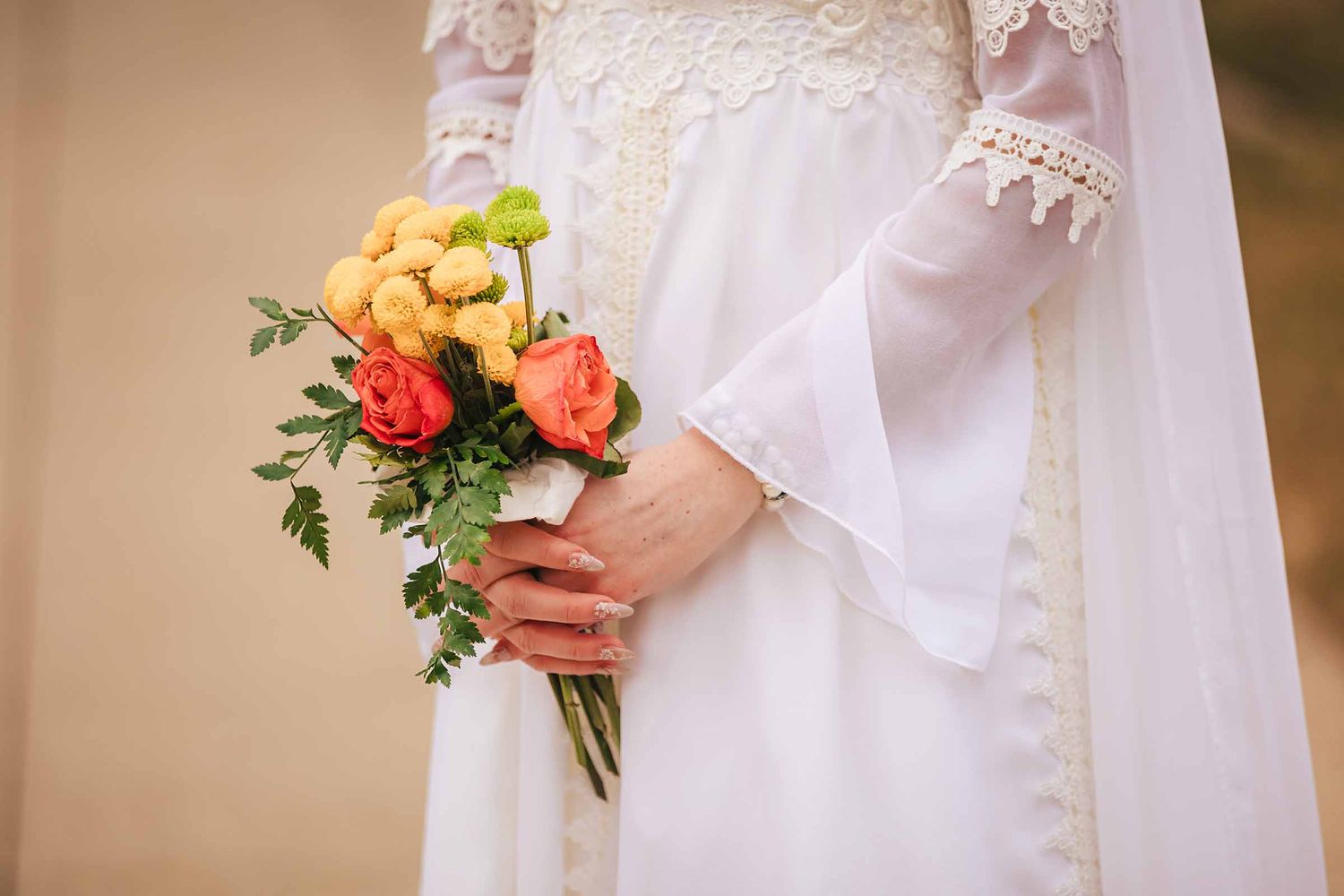 Bride holds a vibrant elopement bouquet of yellow and coral roses with greenery at Boston Massachusetts Temple in Belmont, MA