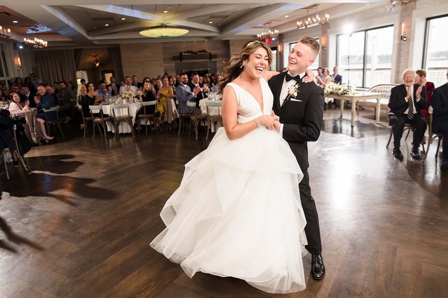 The bride and groom enjoy a joyous laugh together during their first dance.