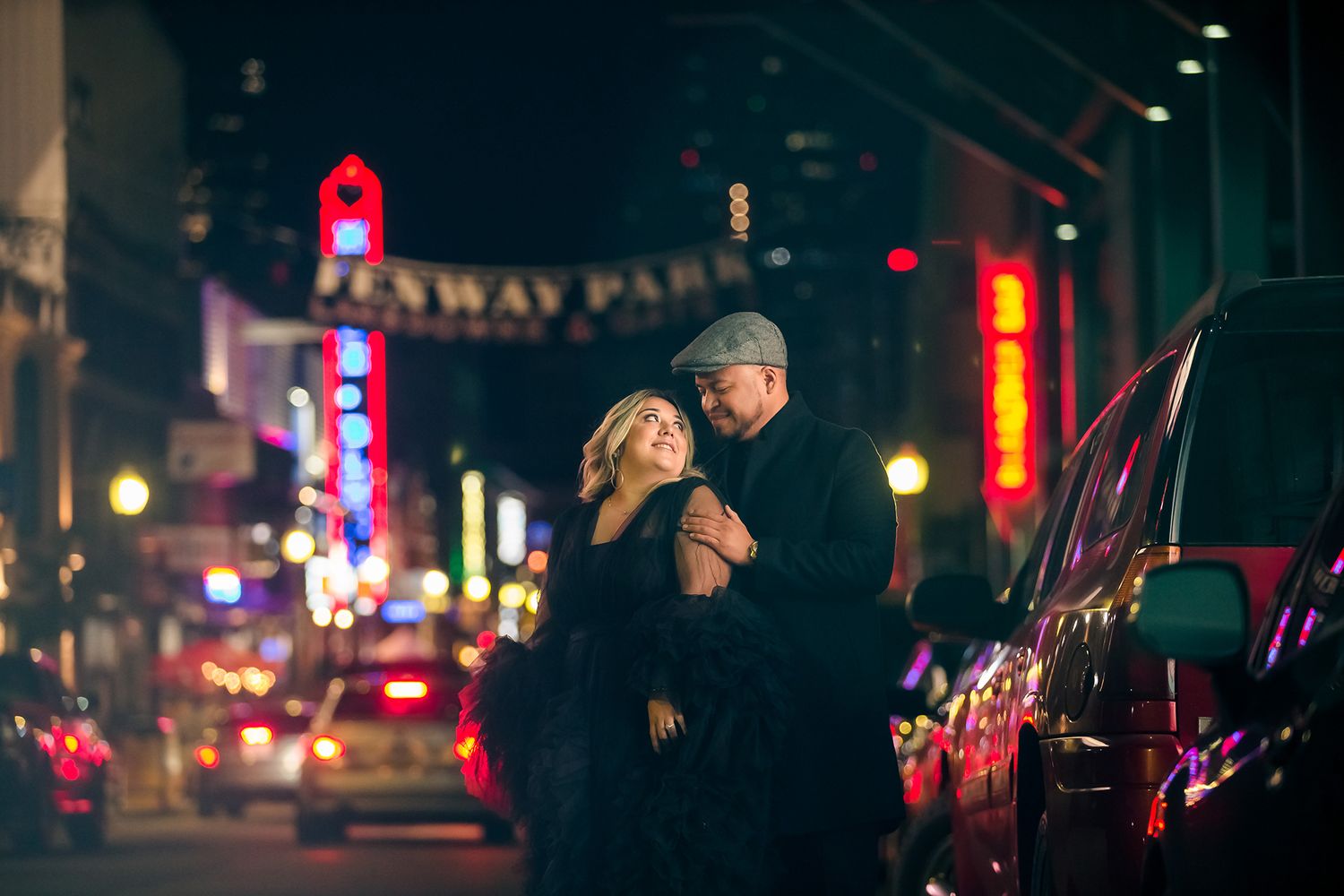 The engaged couple pose for a dramatic nighttime portrait on the street in front of Fenway Park.