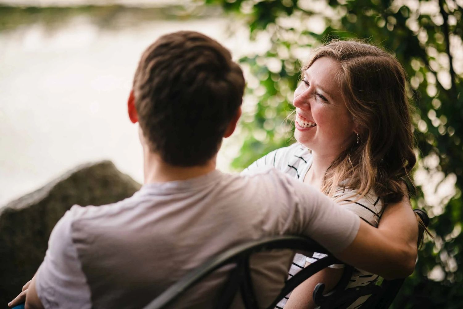 A couple embraces and laughs together outdoors, surrounded by ivy-covered walls.  Engagement at Borderland State Park, North Easton, MA