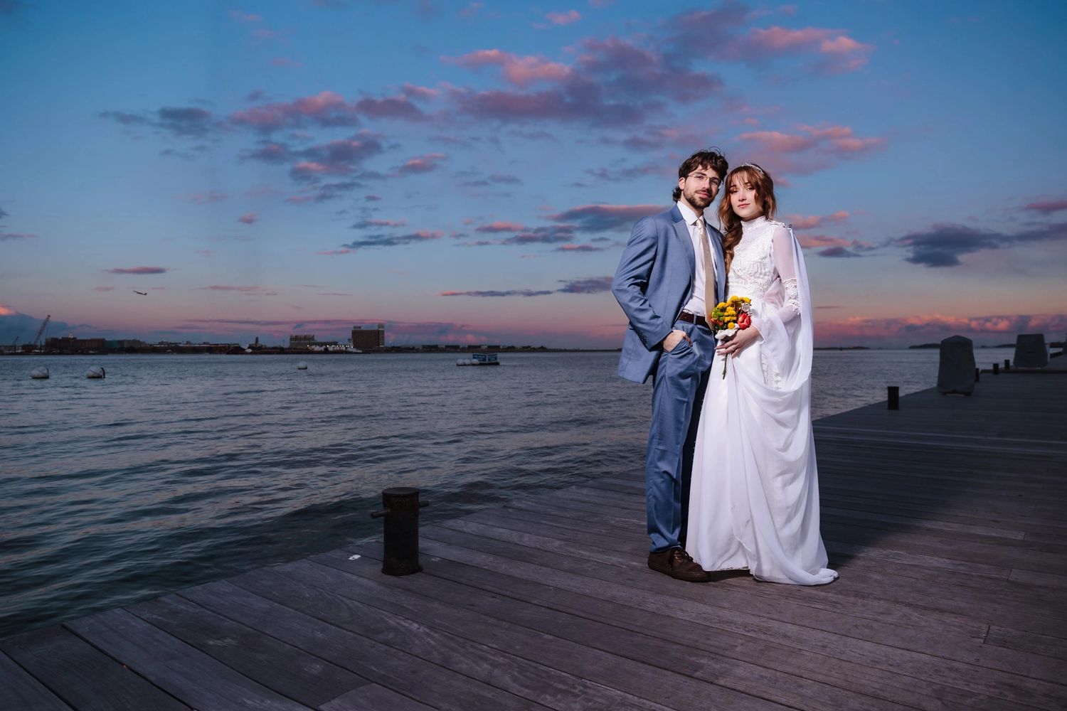 Bride and groom hold each other close on a wooden dock at Fan Pier Park, at sunset during their Boston Elopement Portrait Session