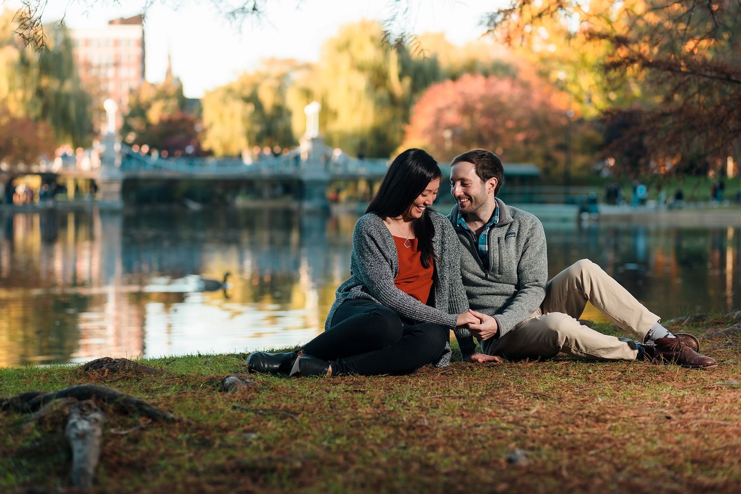 The bride and groom hold hands while relaxing near the Pond during their engagement session at the Boston Public Garden