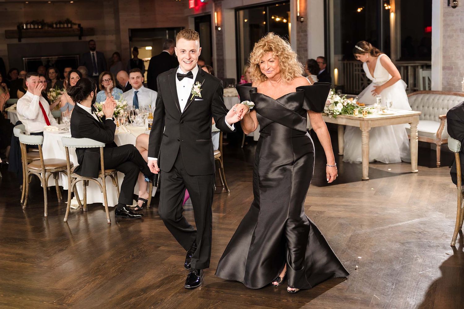 The groom and the his mother walk onto the dance floor.