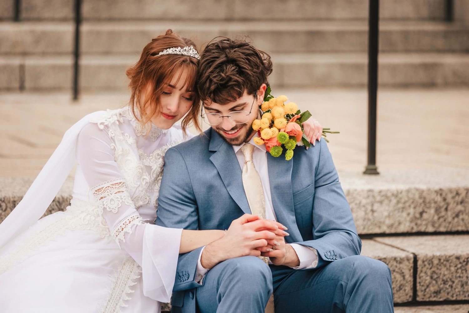 Bride and groom sit on stone steps during their Boston Massachusetts Temple elopement, admiring her ring together