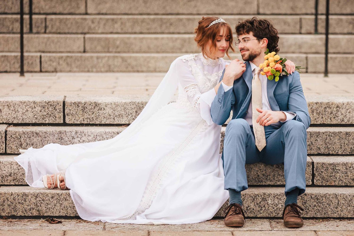 Bride leans toward groom on stone steps during their Boston Massachusetts Temple elopement, holding a yellow bouquet