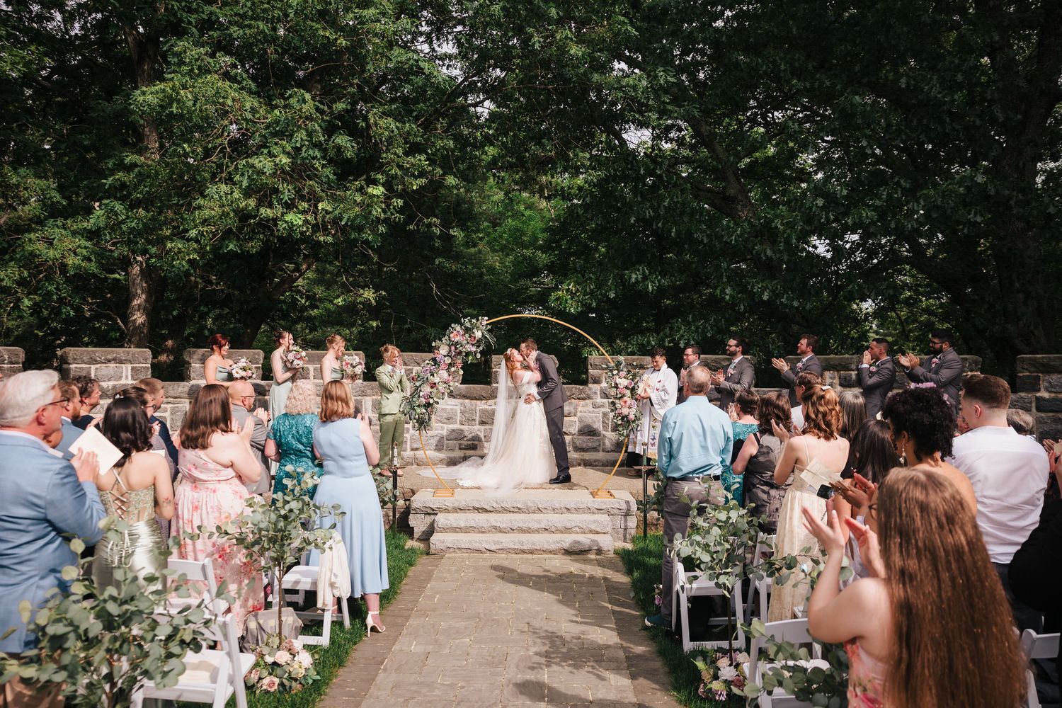 Bride and groom kissing after their ceremony as guests applaud, at Searles Castle in Windham, New Hampshire.