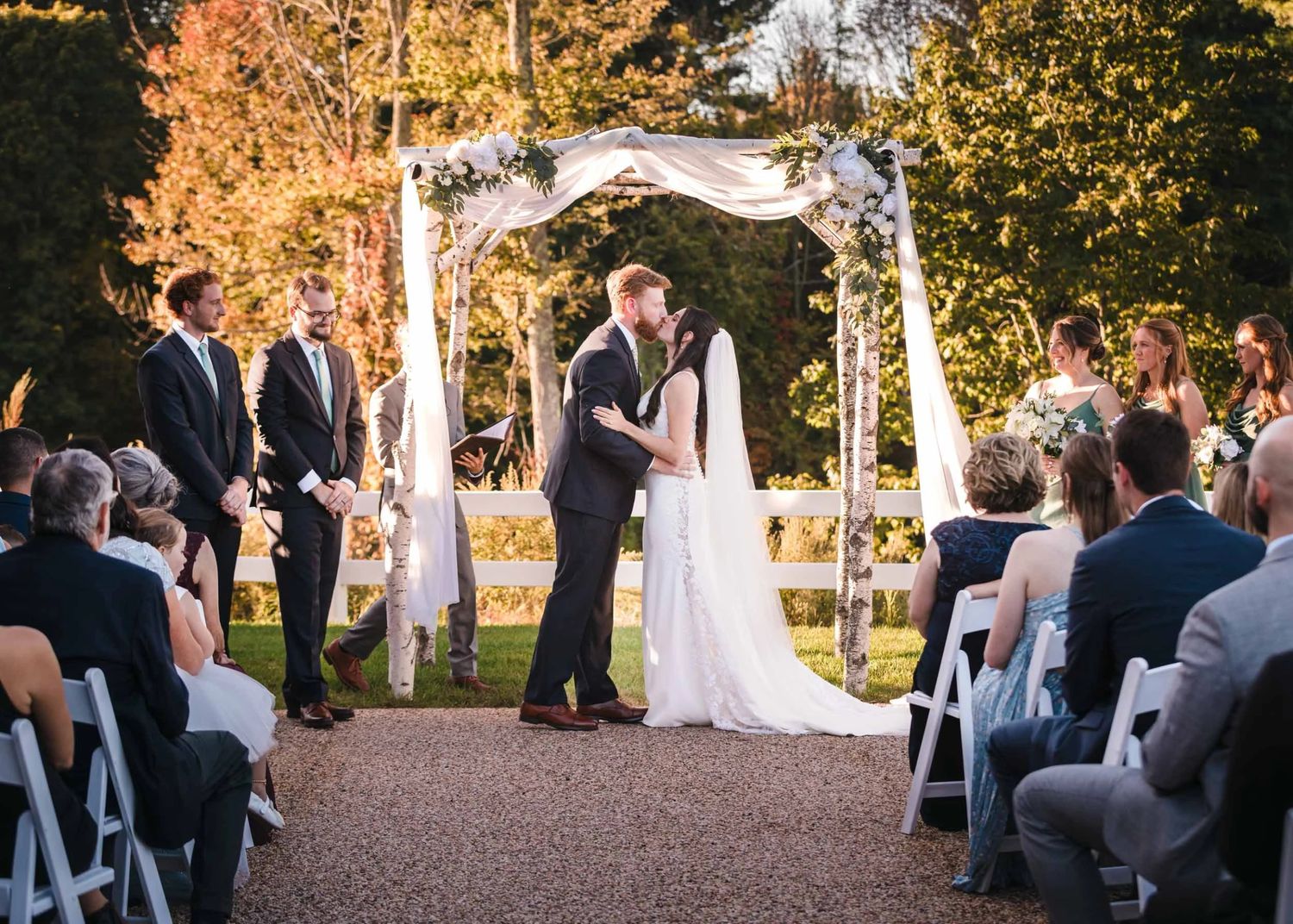 The bride and groom exchange a passionate kiss at the end of their summer wedding ceremony at the Barn at Grand National.
