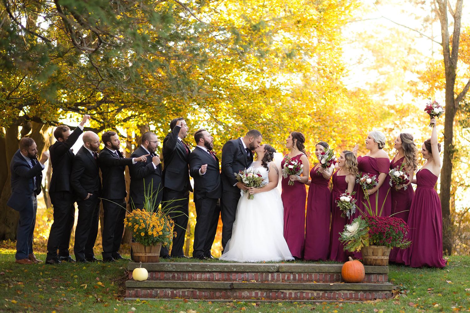 The entire bridal parts cheers the bride and groom on in a kiss.