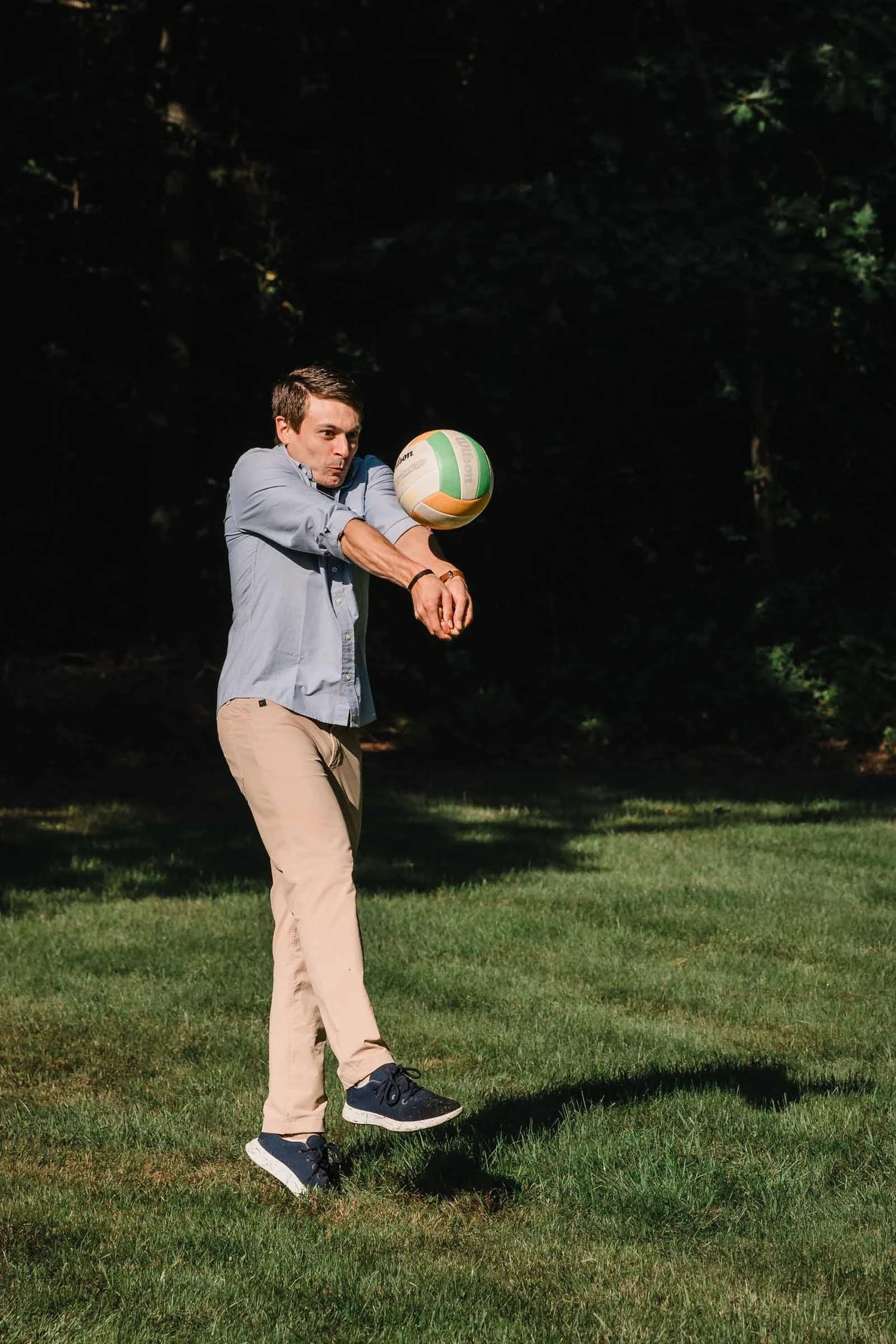 Young man passing a volleyball to himself while standing on grass. Engagement at Borderland State Park, North Easton, MA