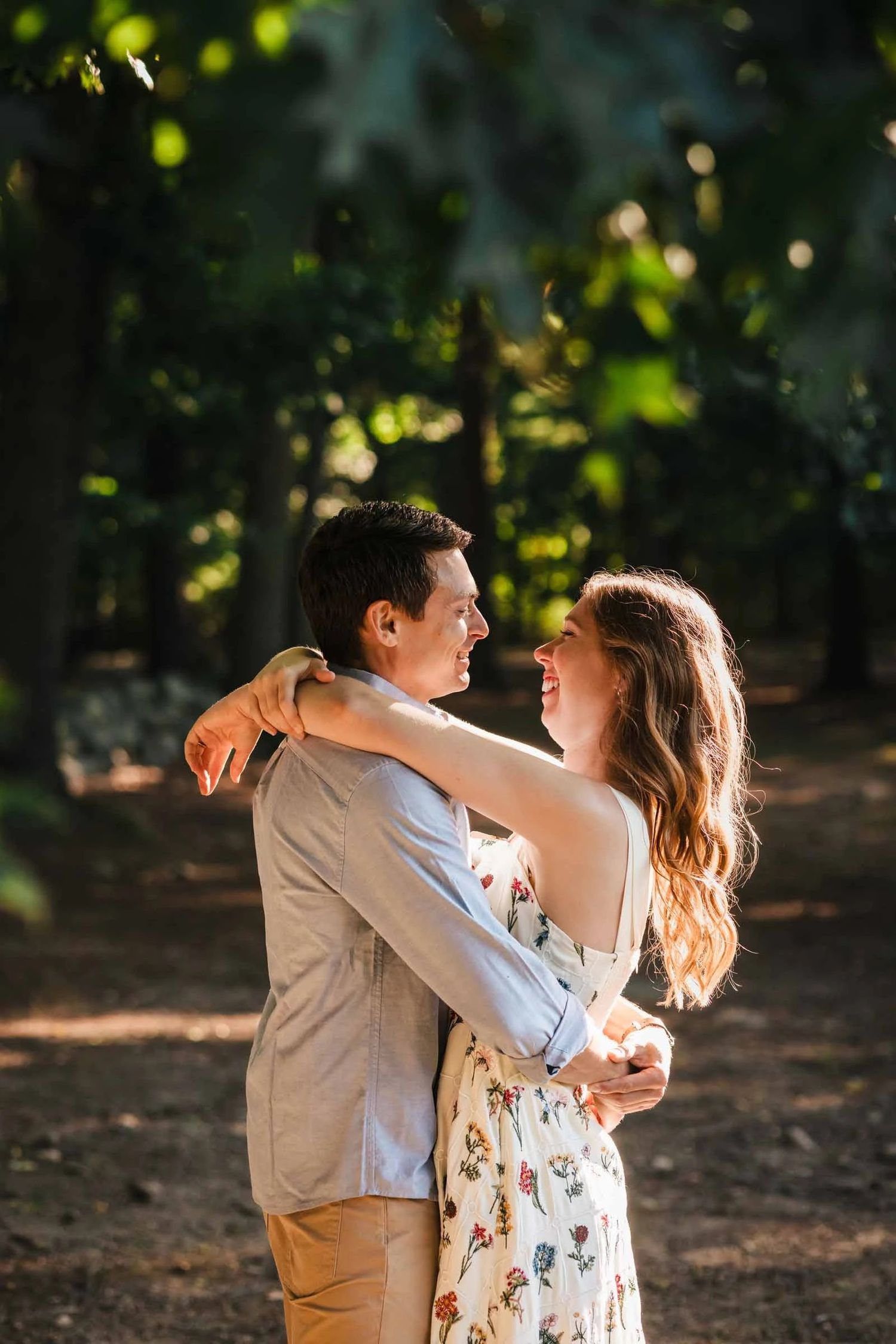 Couple embracing and gazing at each other in dappled forest light during golden hour. Engagement at Borderland State Park, North Easton, M