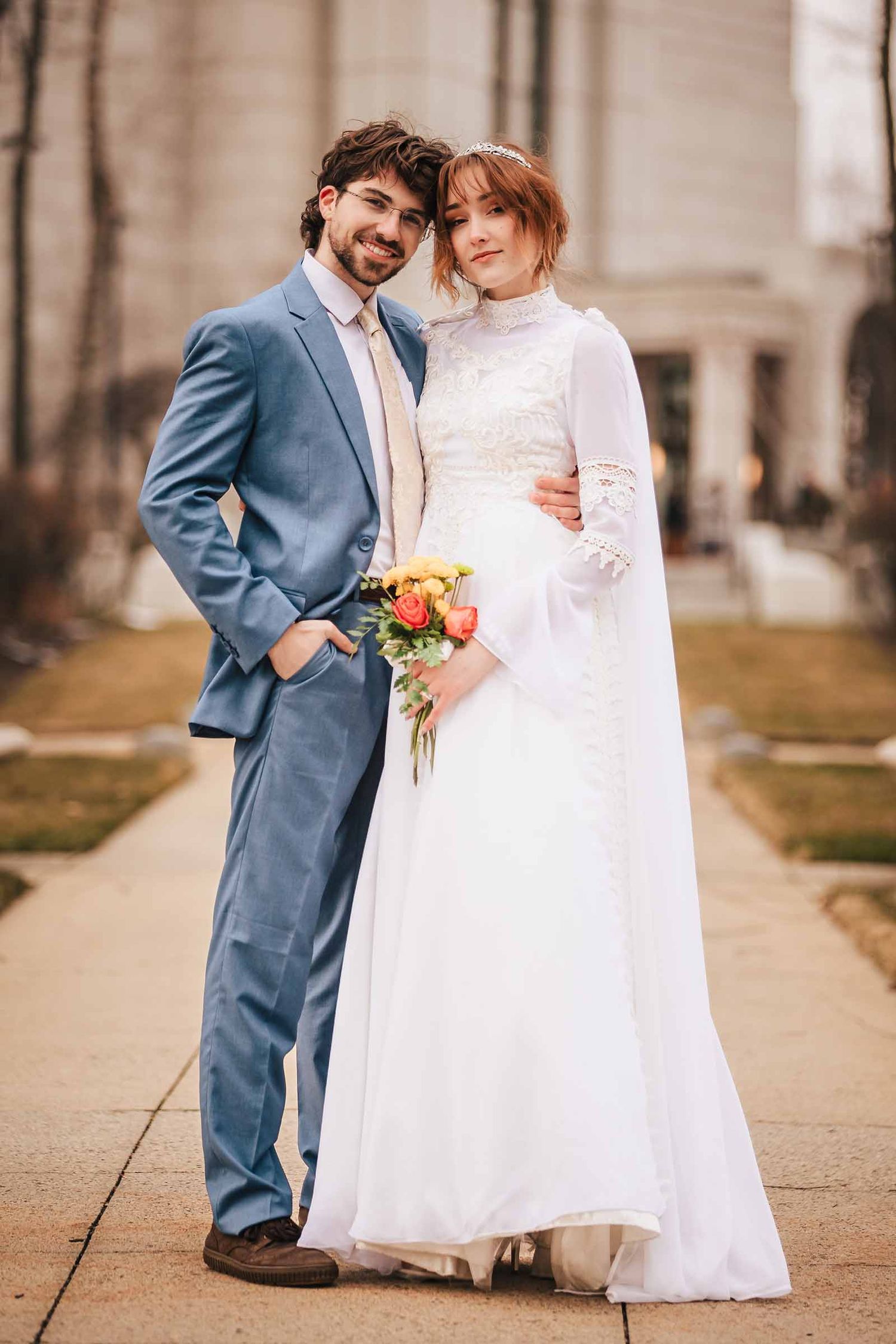 Bride and groom smile together on a Belmont sidewalk during their elopement, holding a colorful bouquet near Boston Massachusetts Temple
