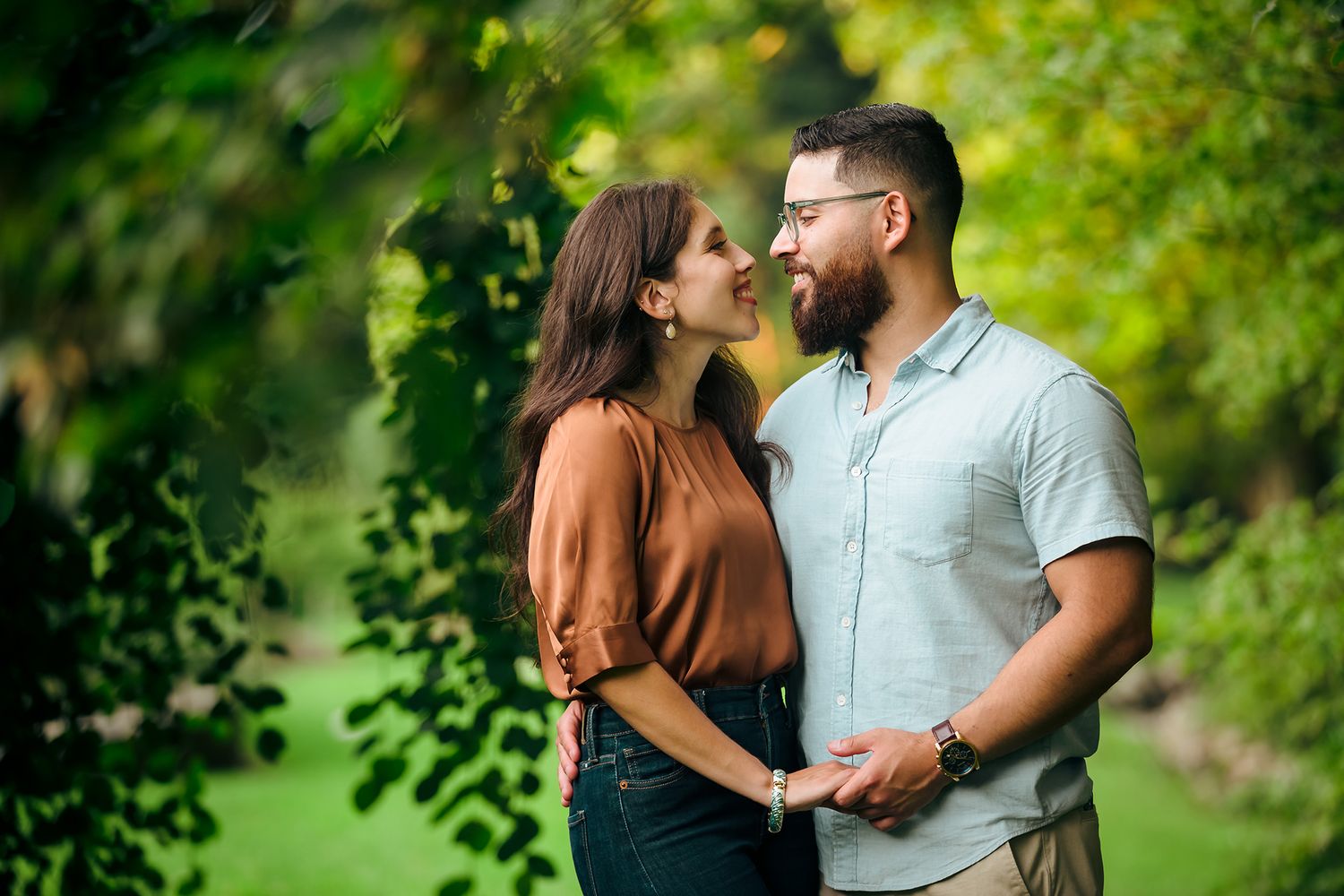 The bride and groom share a lovely smile at their engagement session in the trees at the Arnold Arboretum