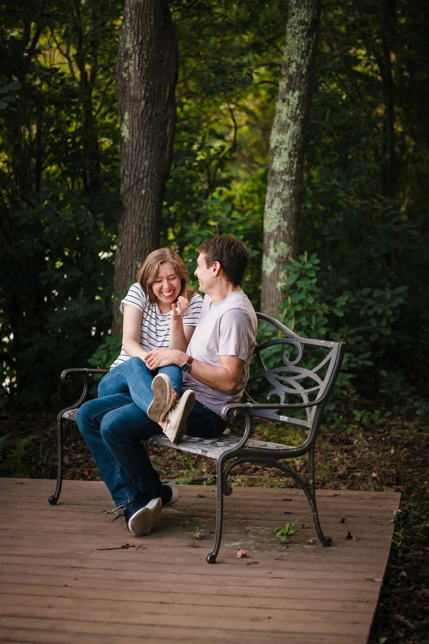 A couple sits close together on a bench, smiling and gazing at each other in an intimate moment. Engagement at Borderland State Park