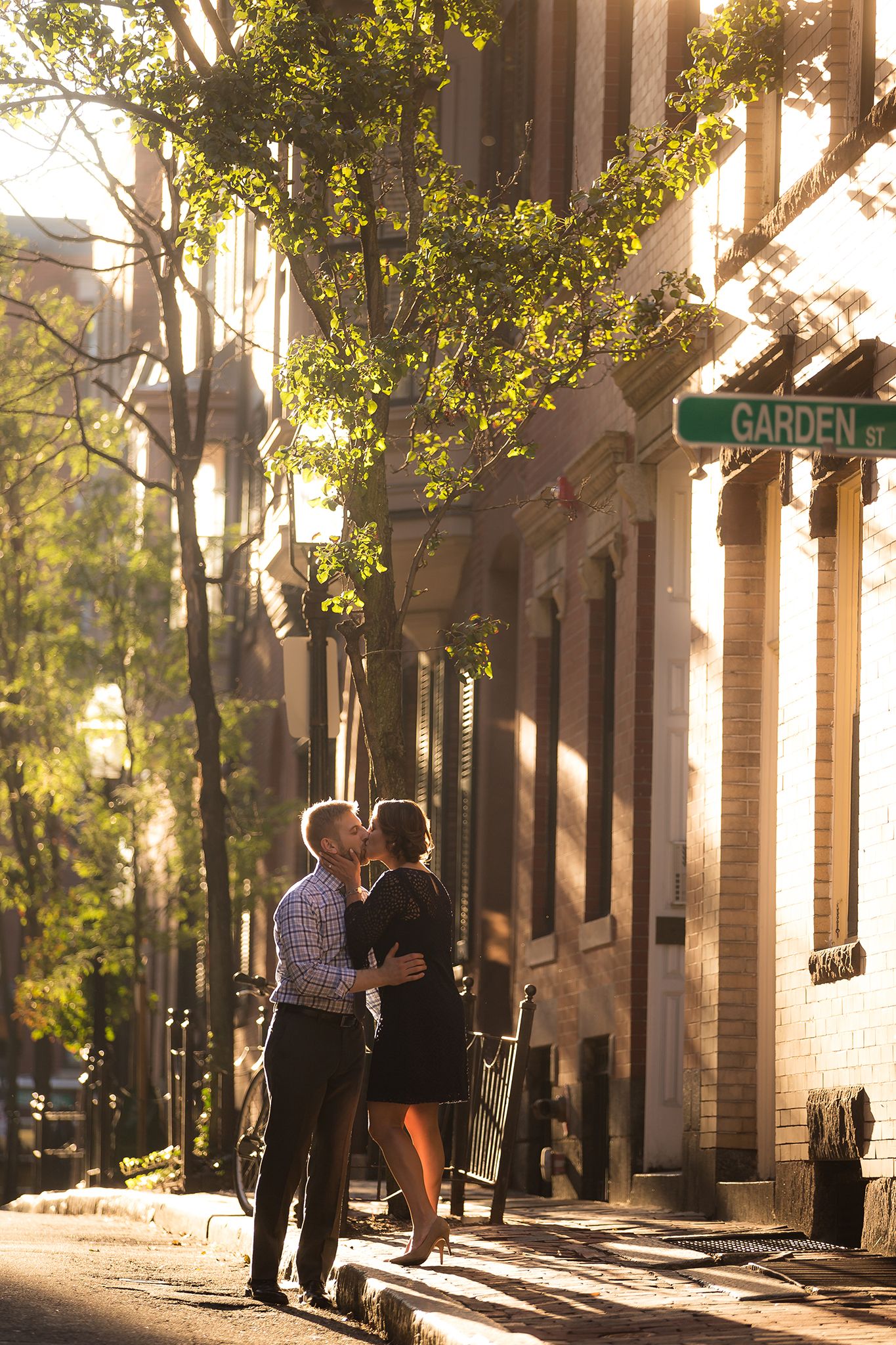 The bride gives the groom a surprise kiss while walking through the Beacon hill neighborhood on a sunny Boston afternoon