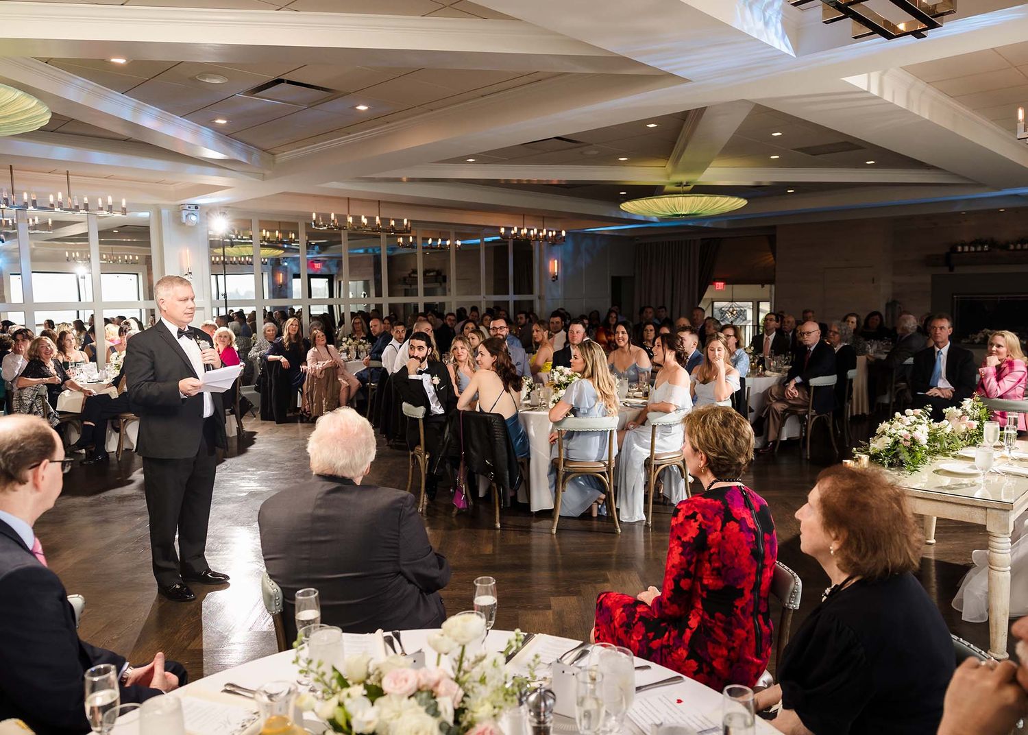 All of the wedding guests look on and listen as the father of the bride give his speech at the wedding reception.